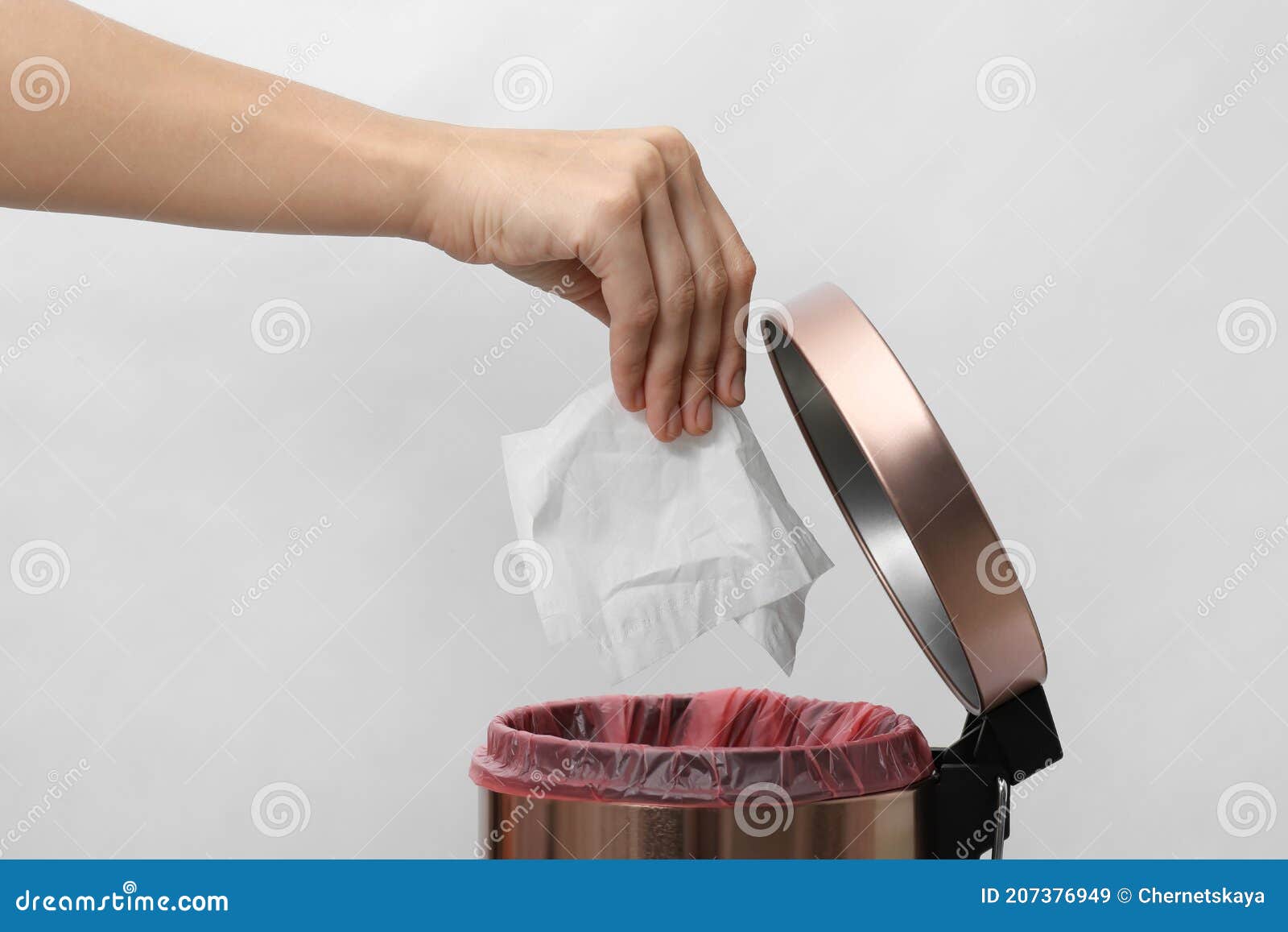 Woman Putting Paper Tissue into Trash Bin on Light Background, Closeup