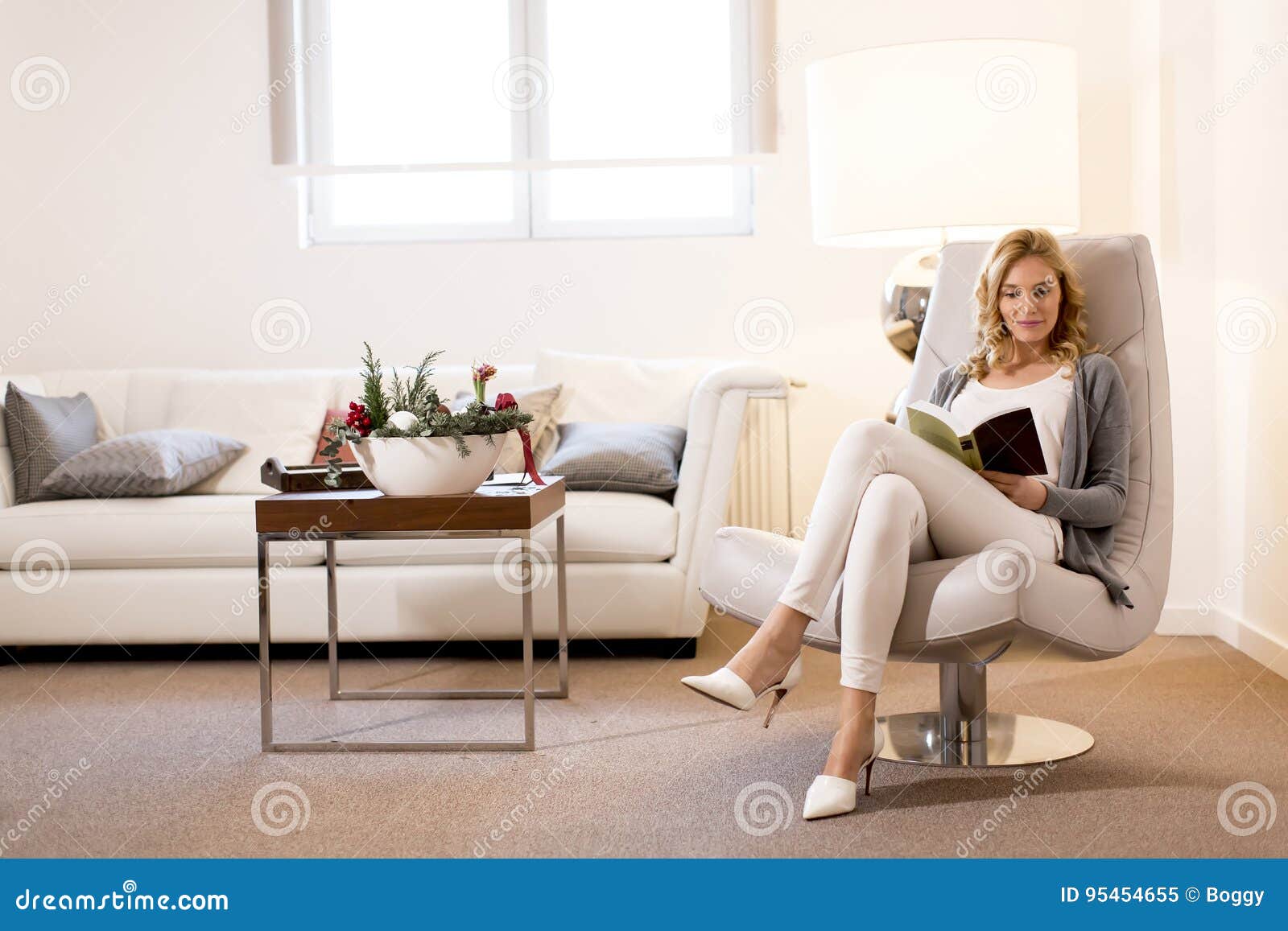 woman reading a book and sitting on comfortable chair at home