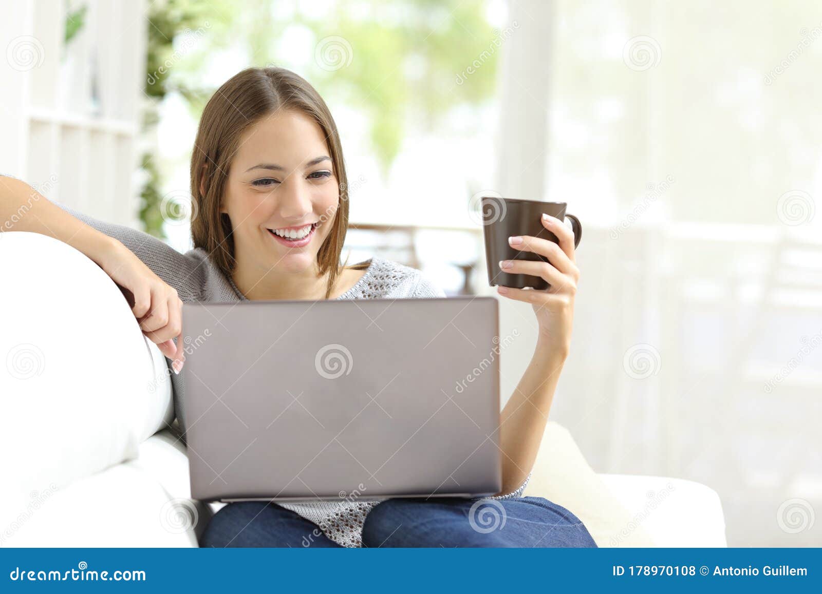 Woman Reading Content on Laptop Holding Coffee Cup Stock Photo - Image ...