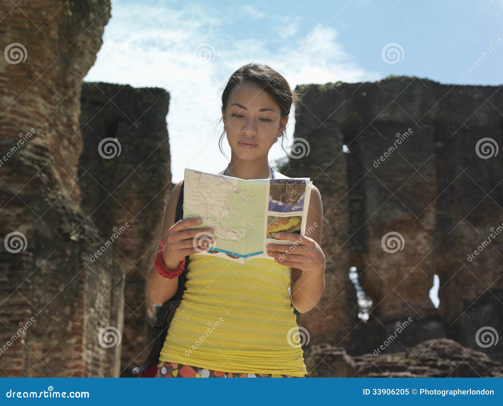 woman reading guidebook with ancient ruins in background