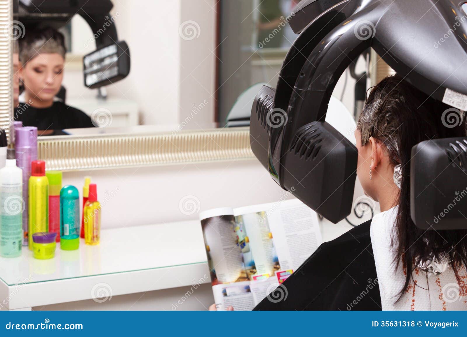 Woman Reading Magazine In Hair Beauty Salon By Hairdresser Stock