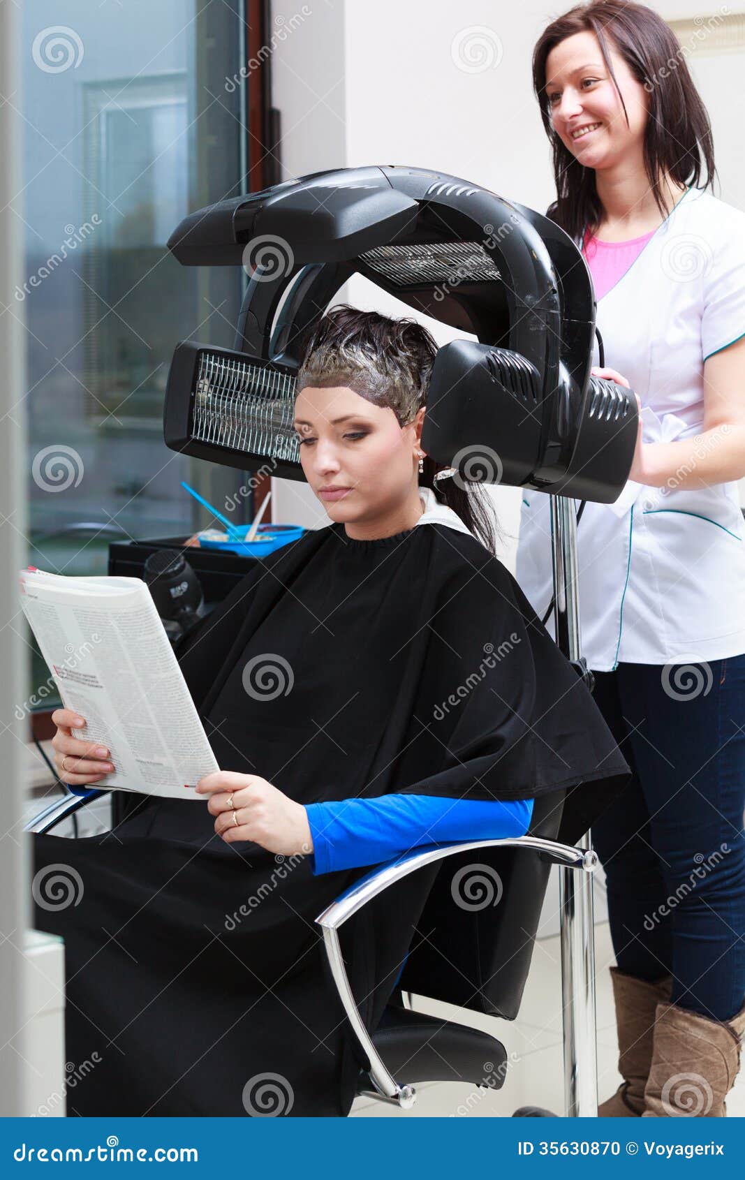 Woman Reading Magazine In Hair Beauty Salon By Hairdresser Stock