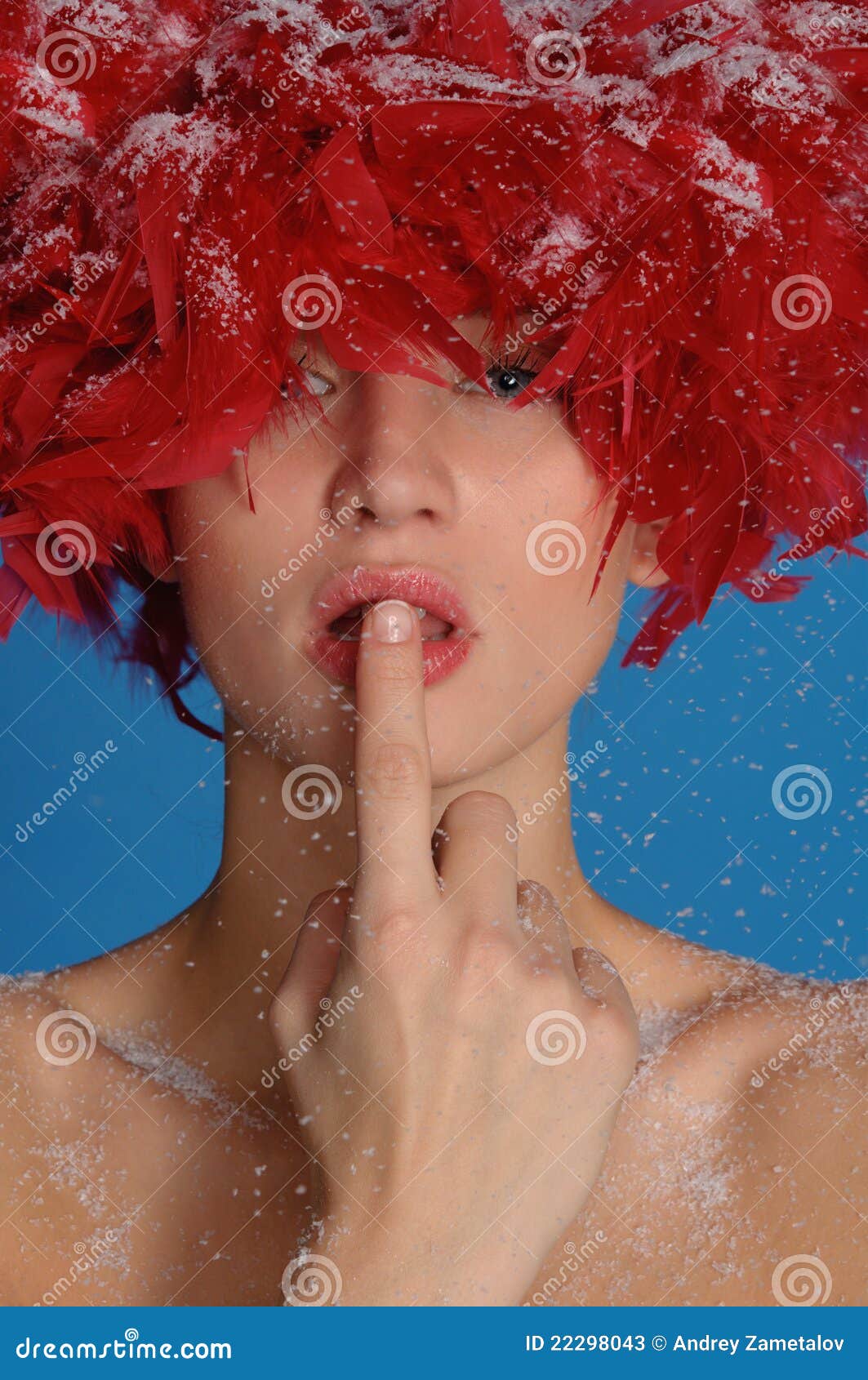 Woman with red feathers in the snow on blue background