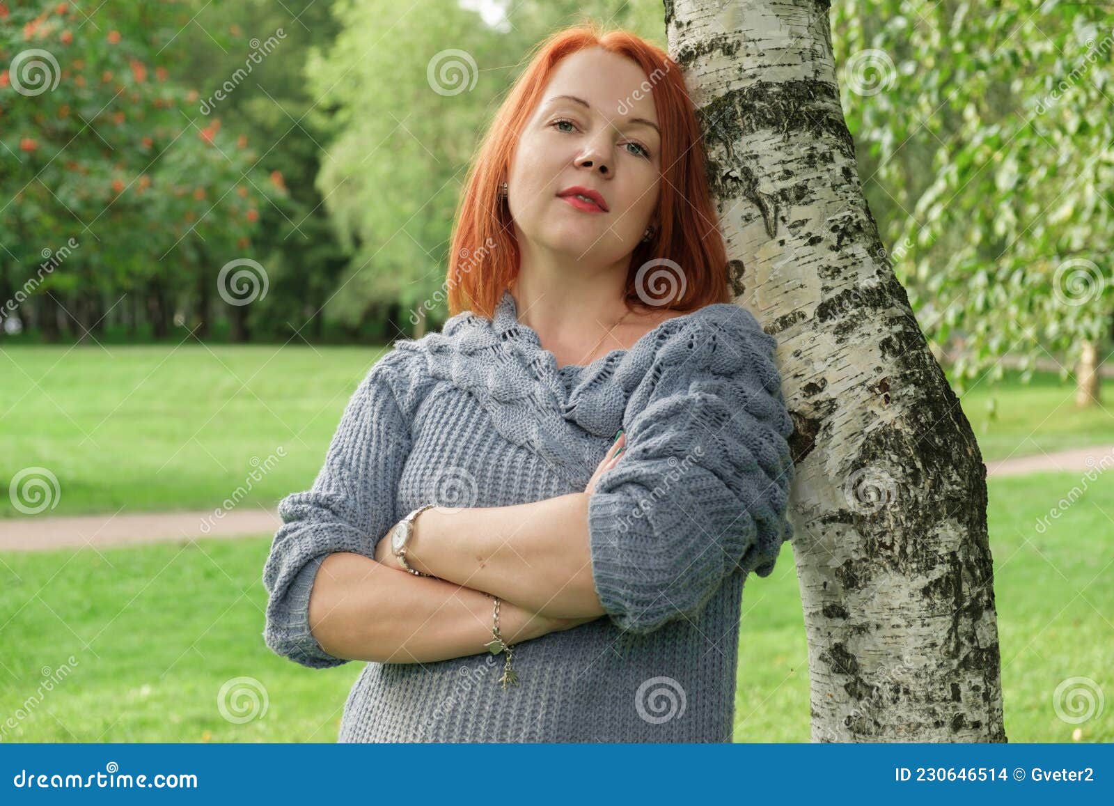 Woman with Red Hair in a Blue Knitted Sweater Stands by a Birch Tree ...