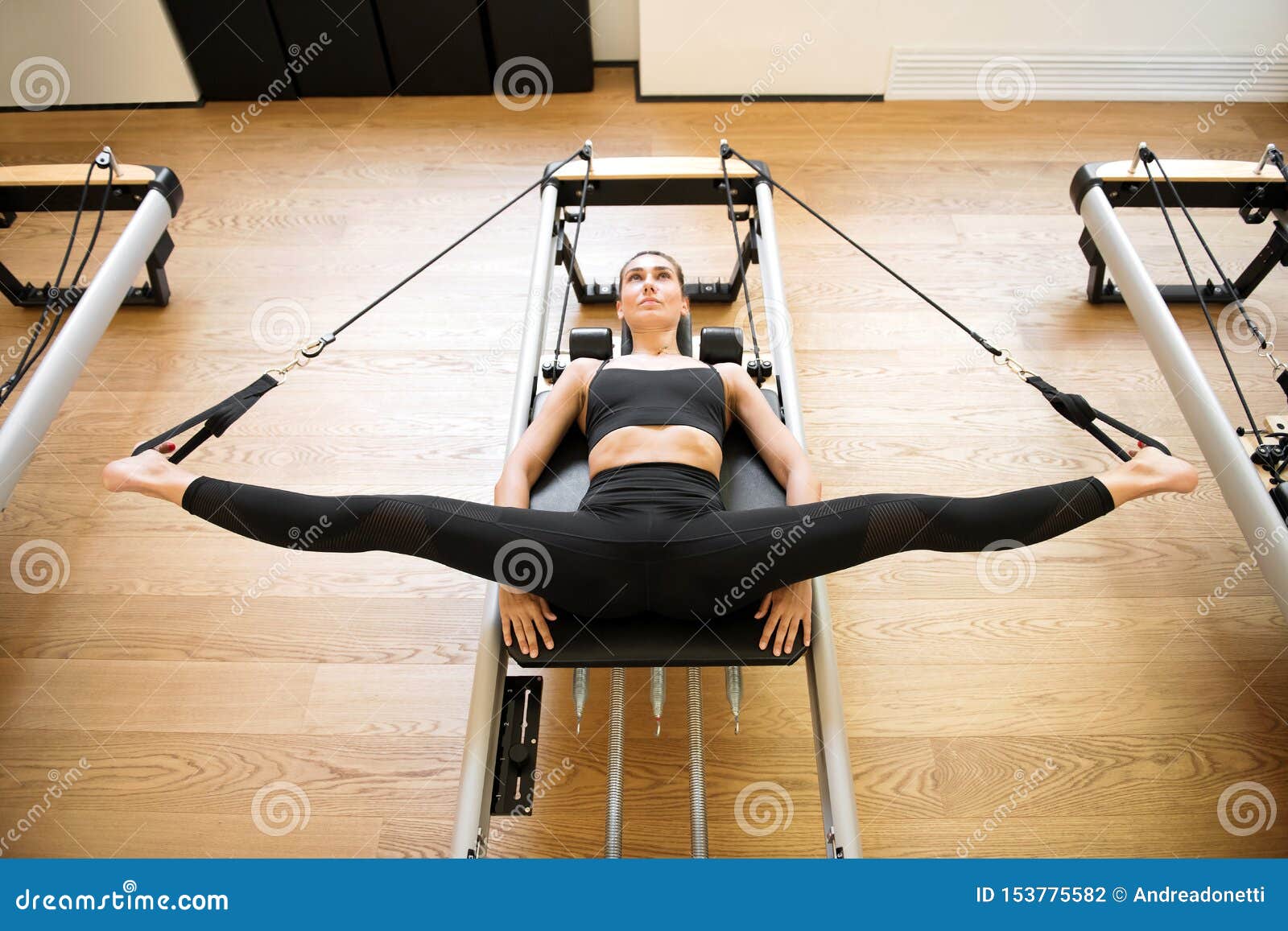 Woman on Reformer Bed Doing Hip Opening Exercises Stock Photo