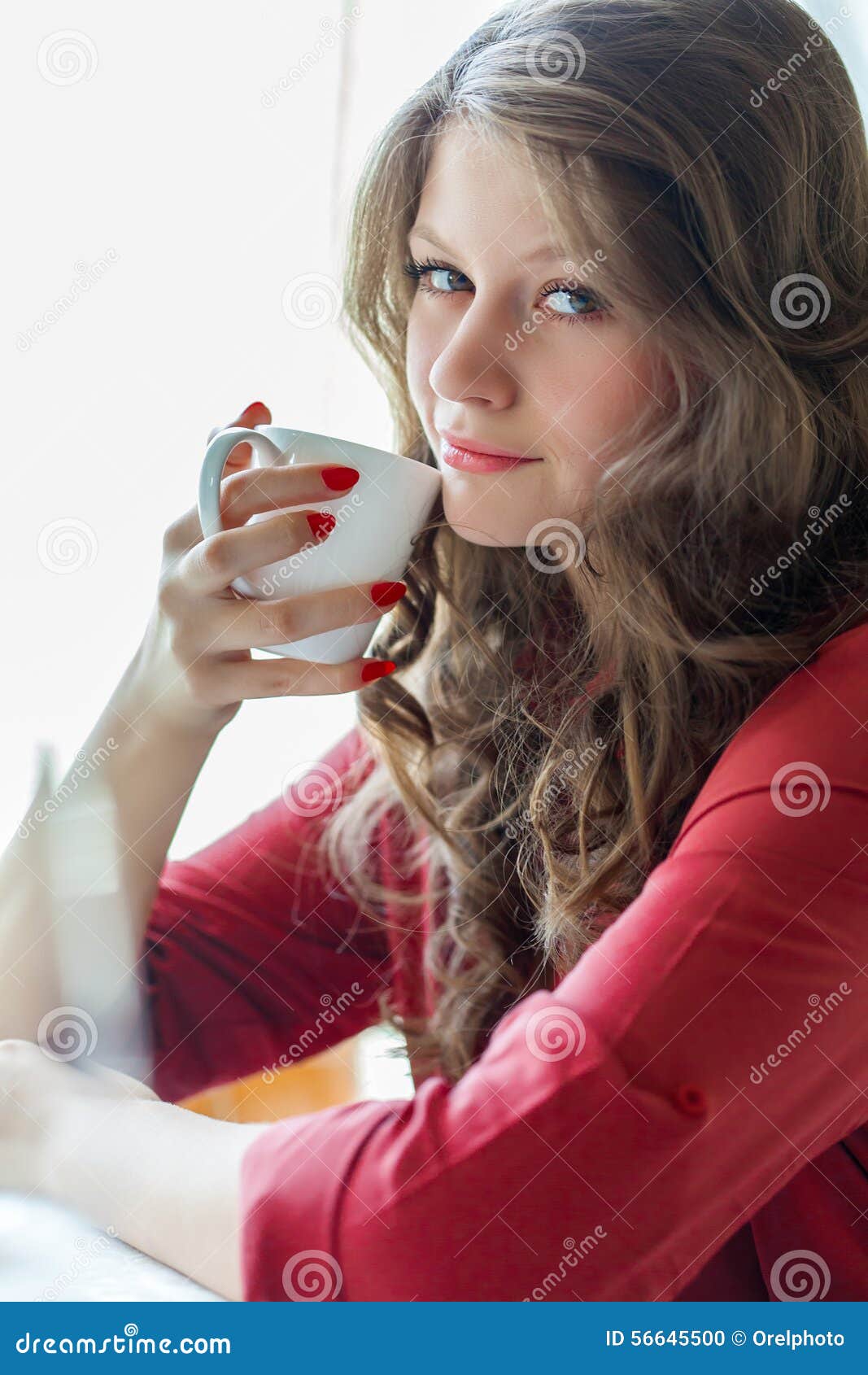 A woman in a restaurant is drinking coffee. A smiling woman in a restaurant is drinking coffee