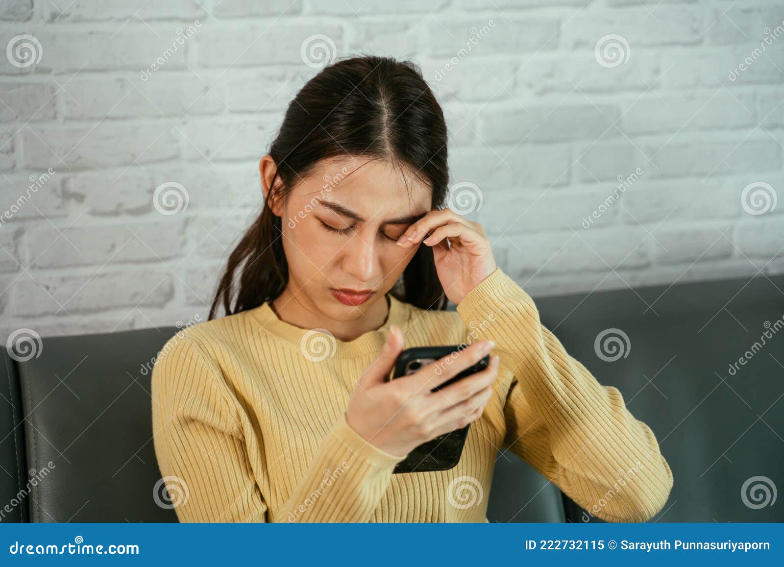 woman rubbing eyes while using phone