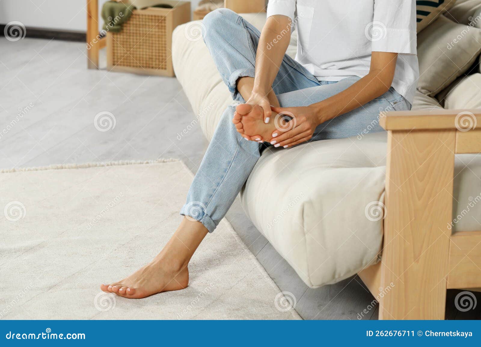 Woman Rubbing Sore Foot On Sofa At Home Closeup Space For Text Stock