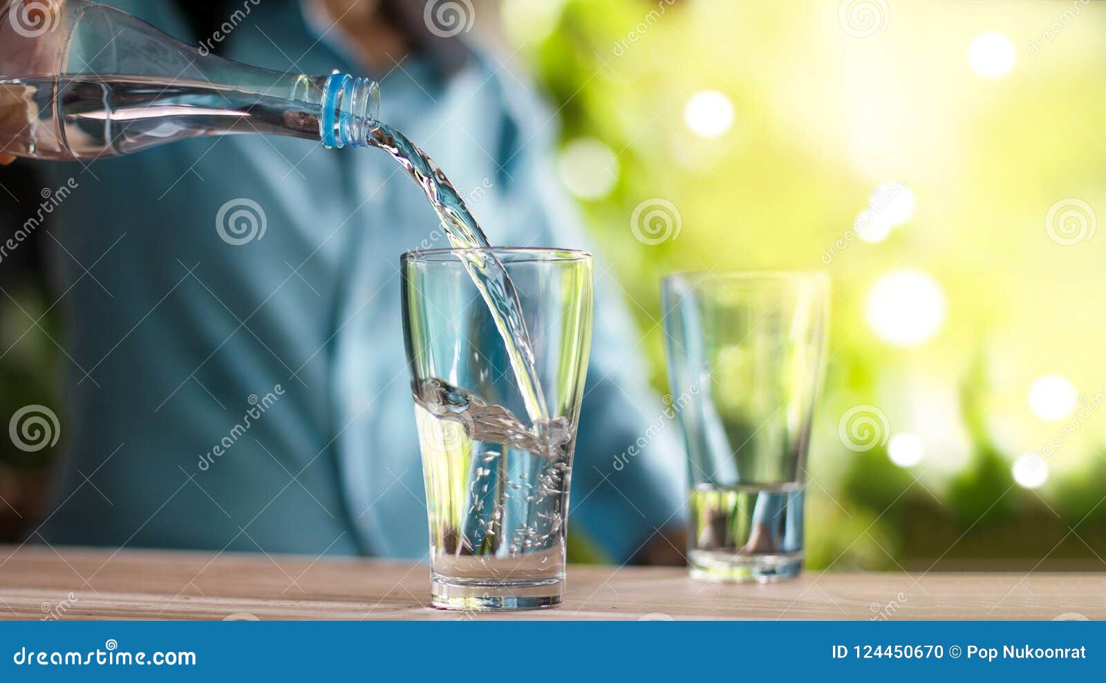 woman`s hand pouring drinking water from bottle into glass