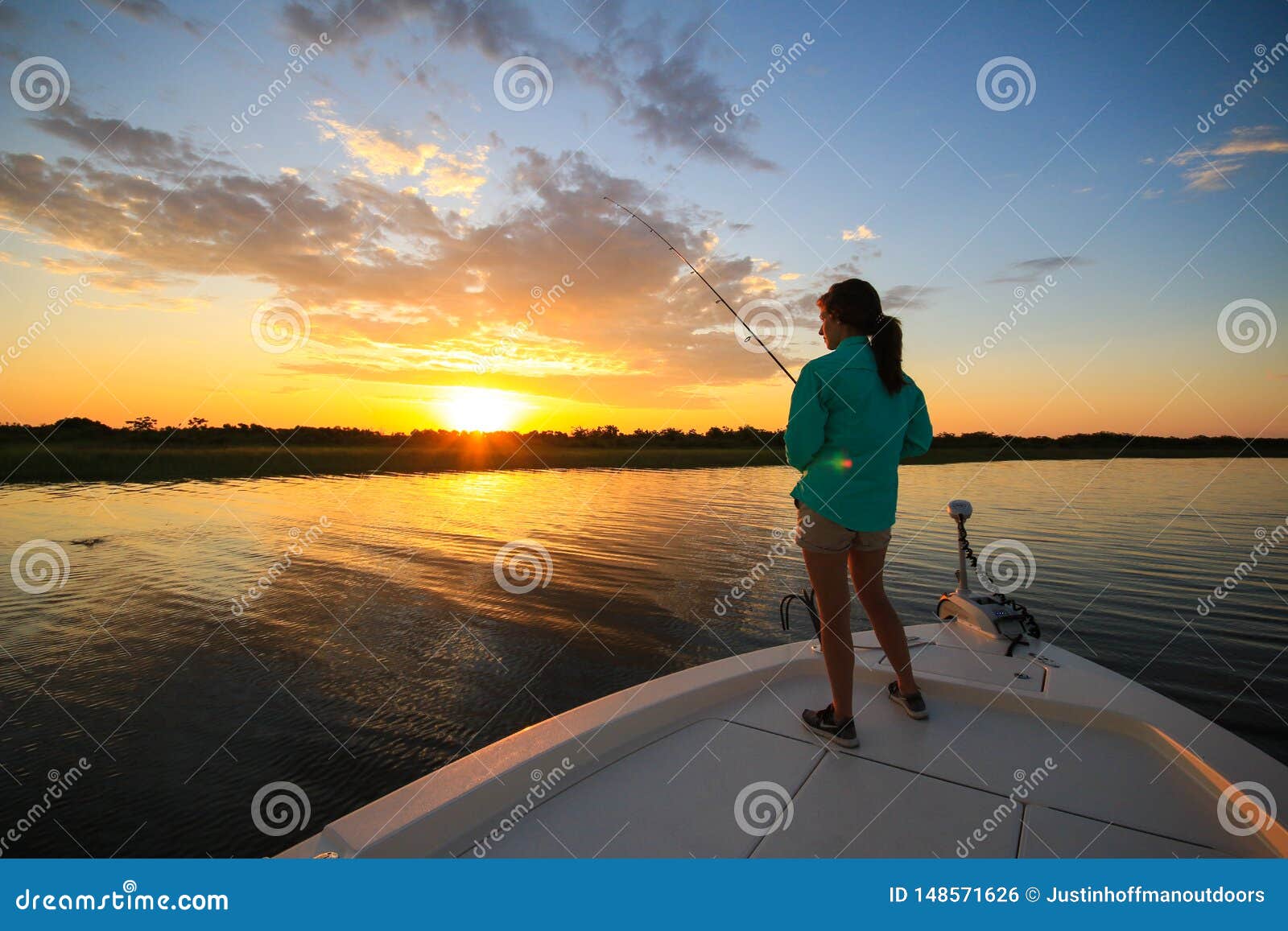woman saltwater fishing casting from boat during sunrise