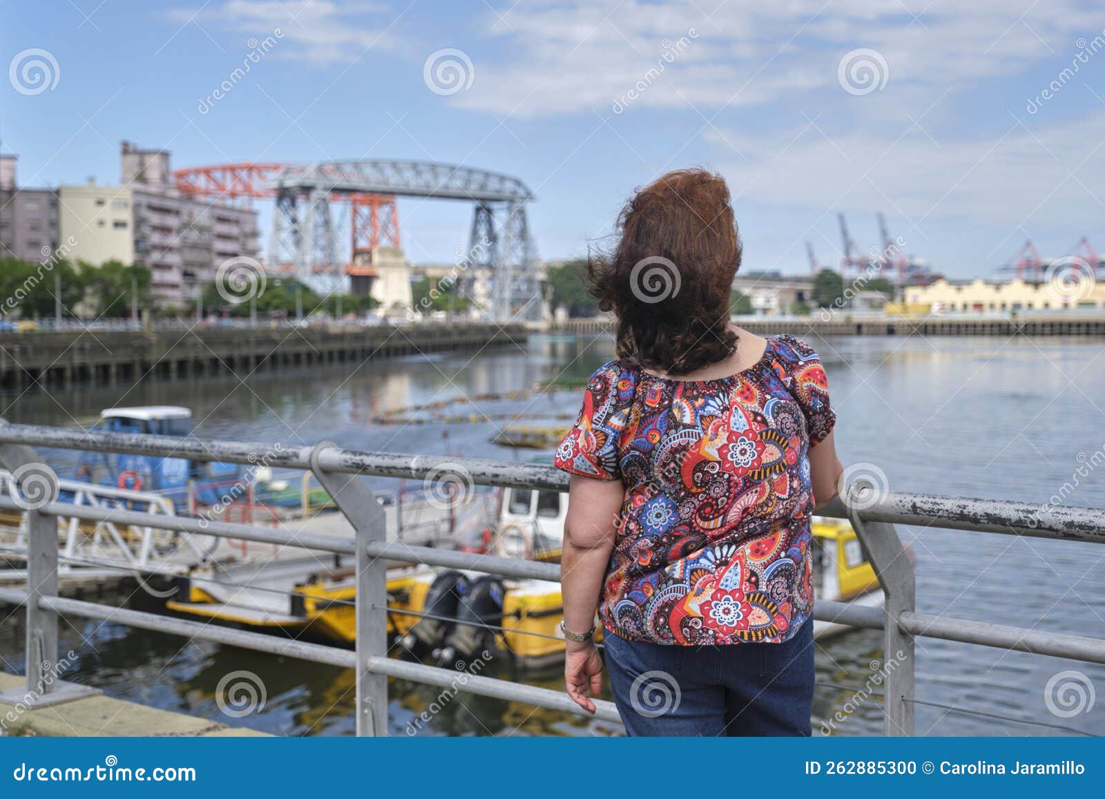 woman seen from the back looking towards the riachuelo, in la boca, buenos aires