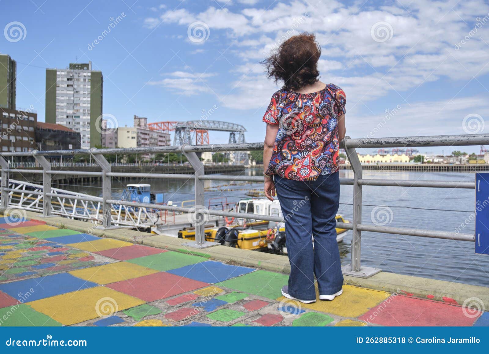 woman seen from the back looking towards the riachuelo, in la boca, buenos aires