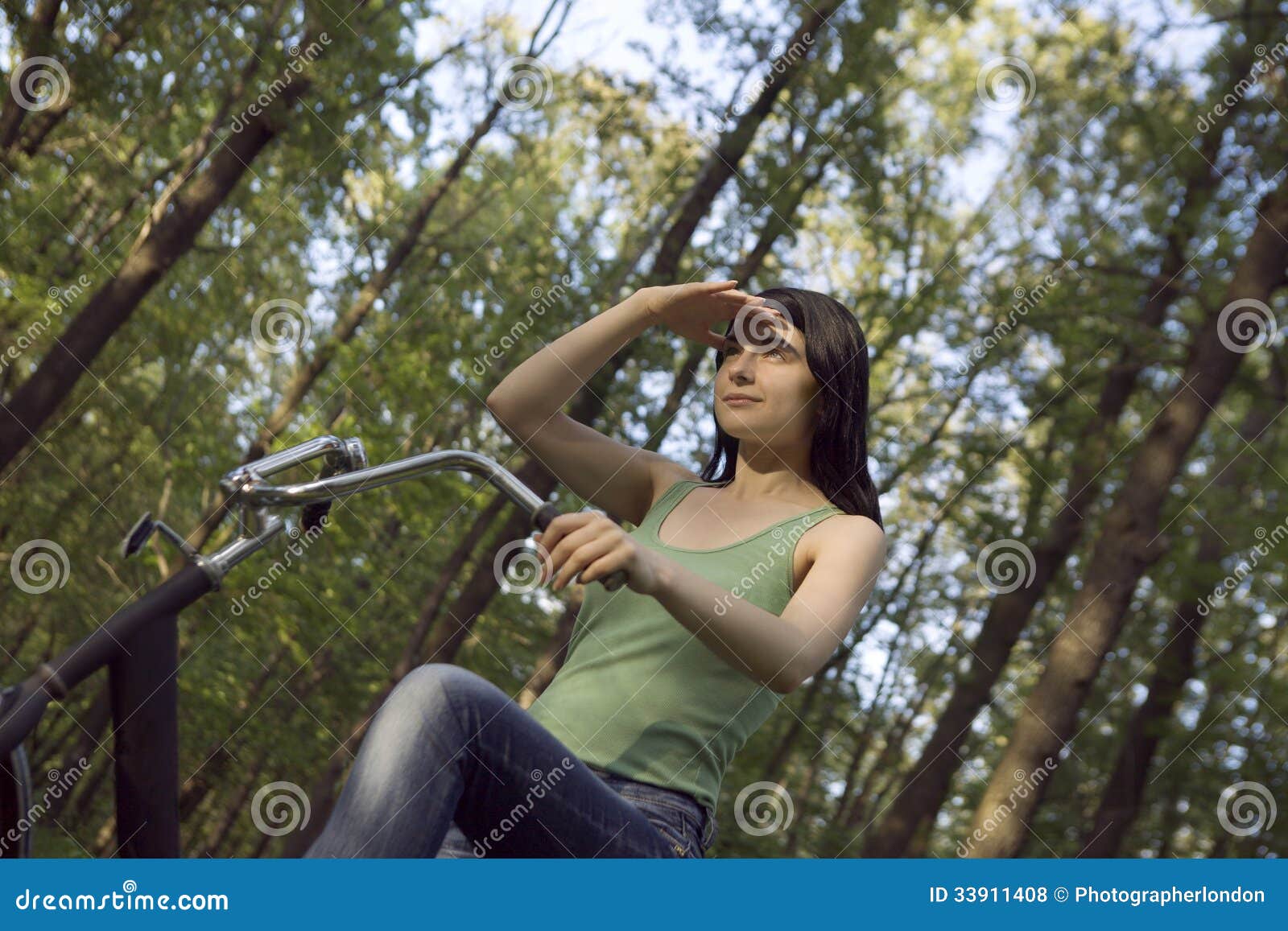 woman shielding eyes while riding bicycle in woodland