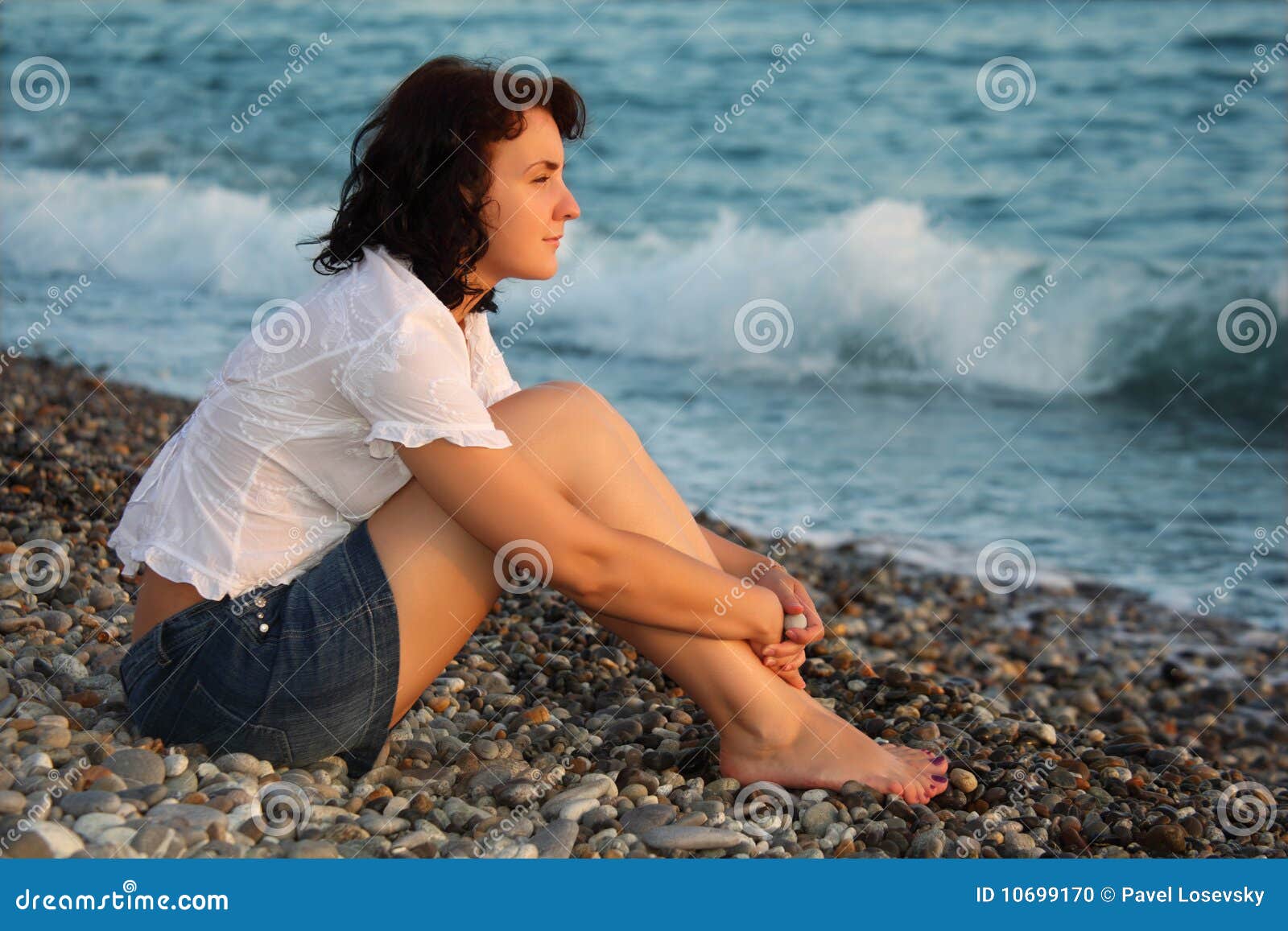 woman sits ashore of sea