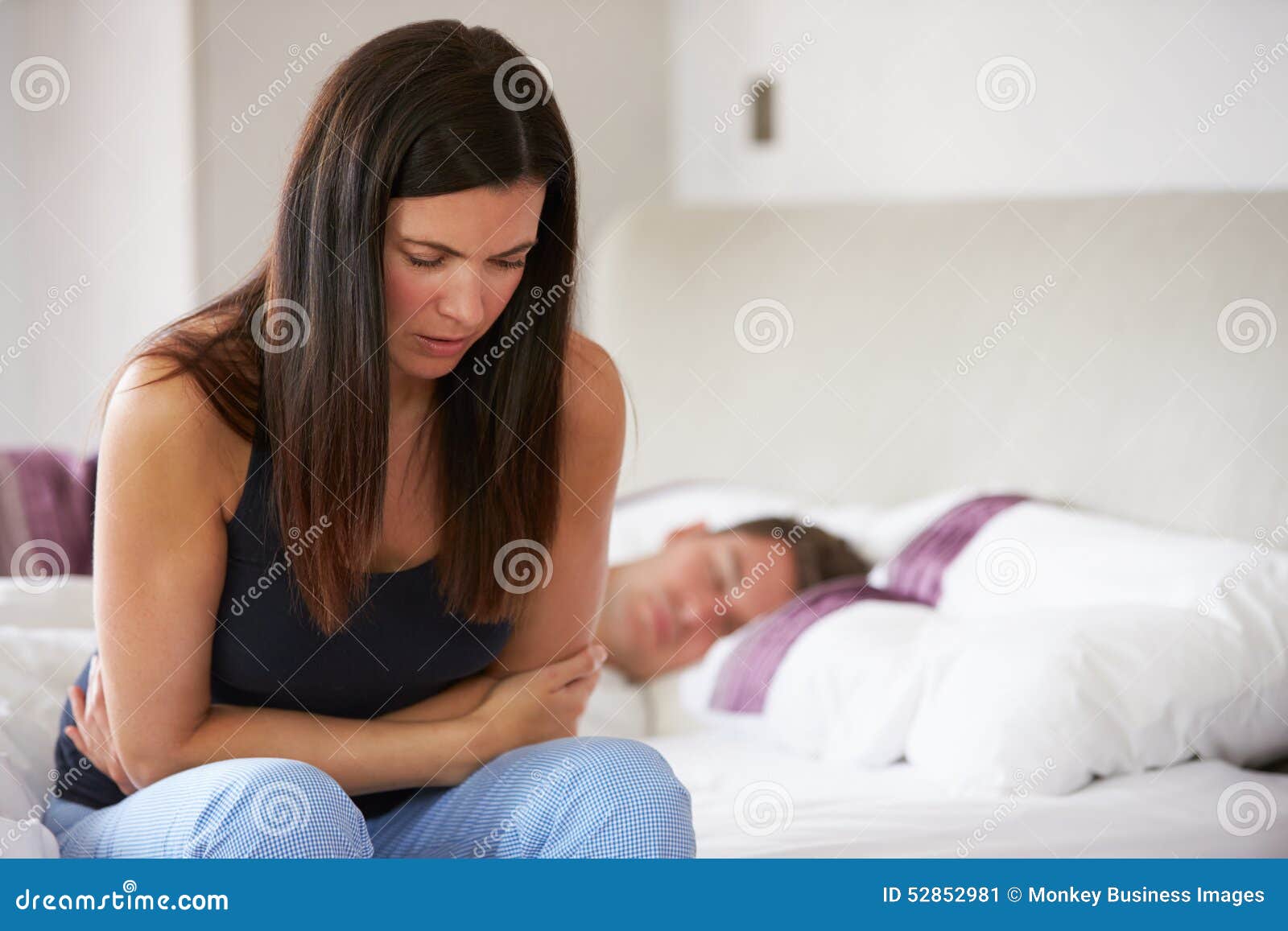 woman sitting on bed and feeling unwell