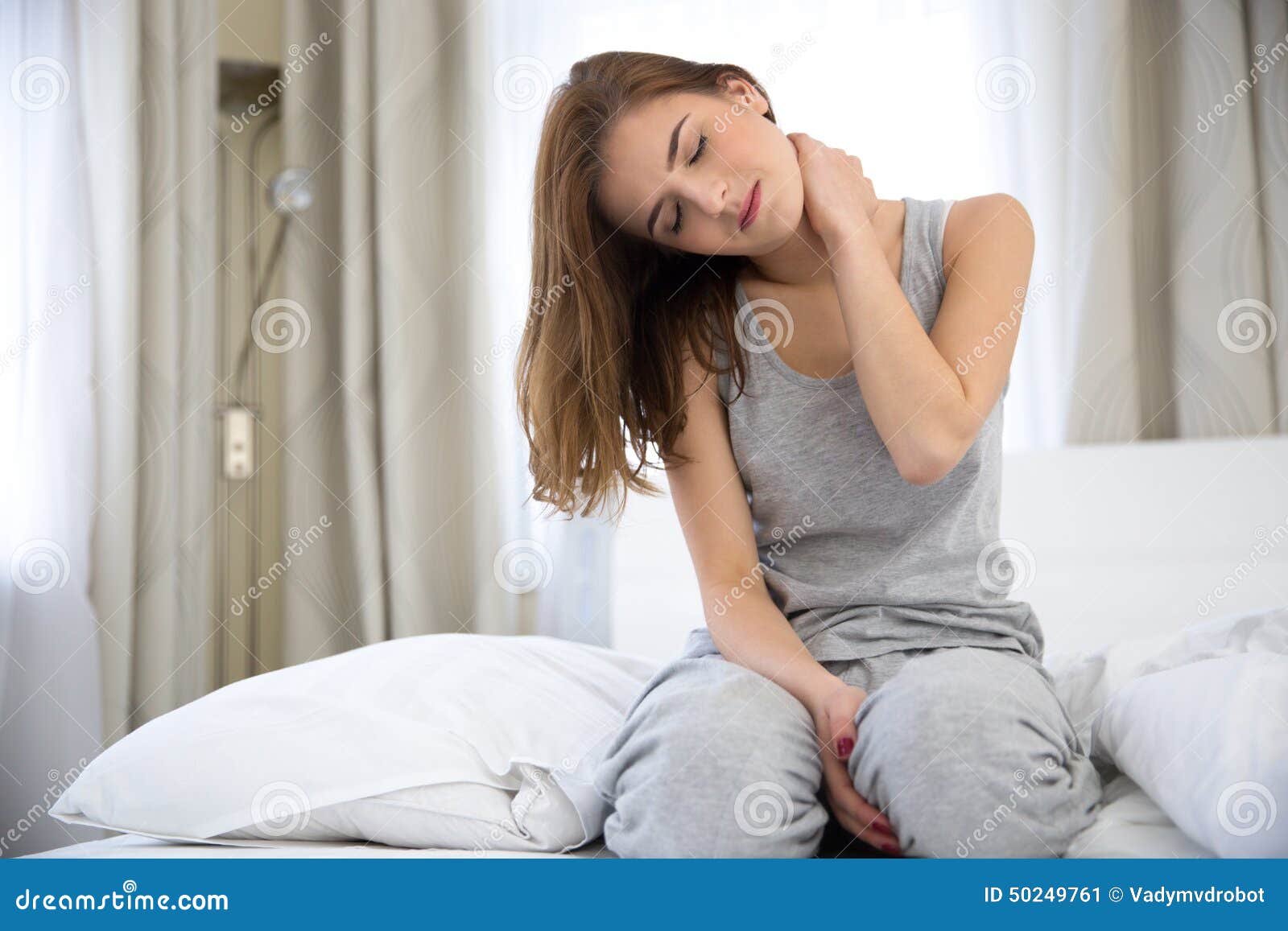 woman sitting on the bed with pain in neck