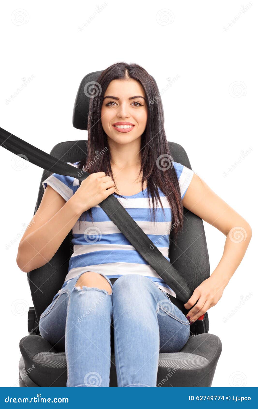 Woman sitting on car seat fastened with a seatbelt. Vertical studio shot of a young woman sitting on a car seat fastened with a seatbelt isolated on white background