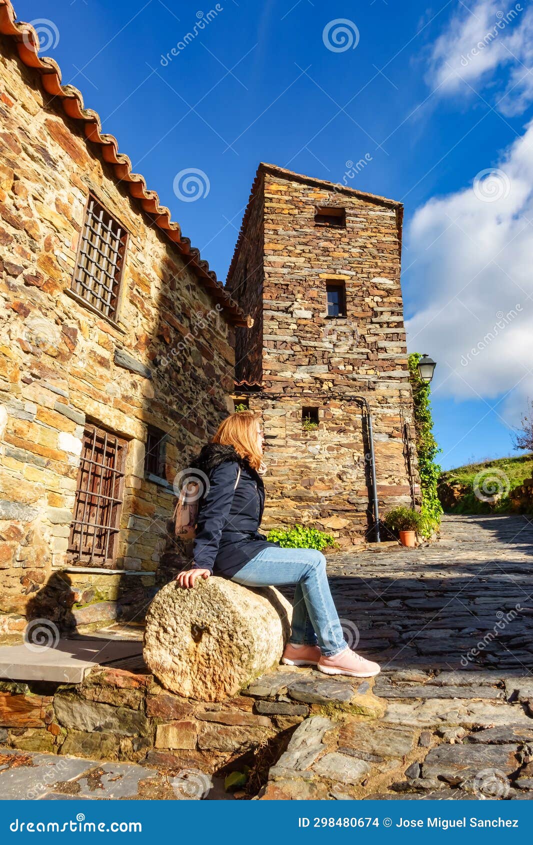 woman sitting on an old millstone in the picturesque village of patones de arriba, madrid.