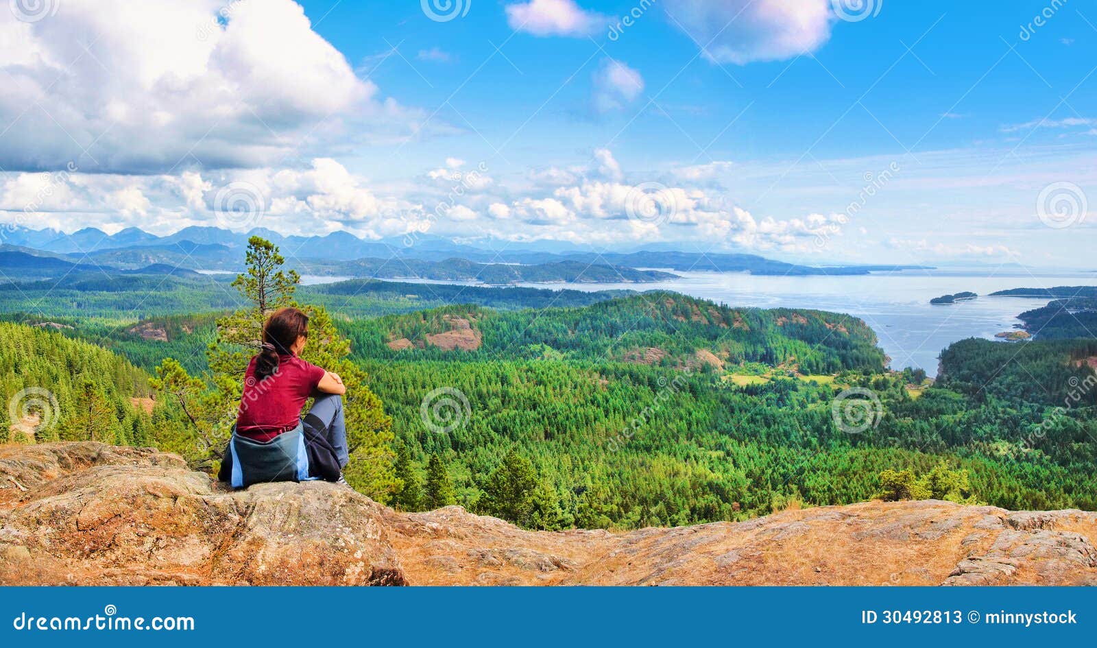 woman sitting on a rock and enjoying the beautiful view on vancouver island, british columbia, canada