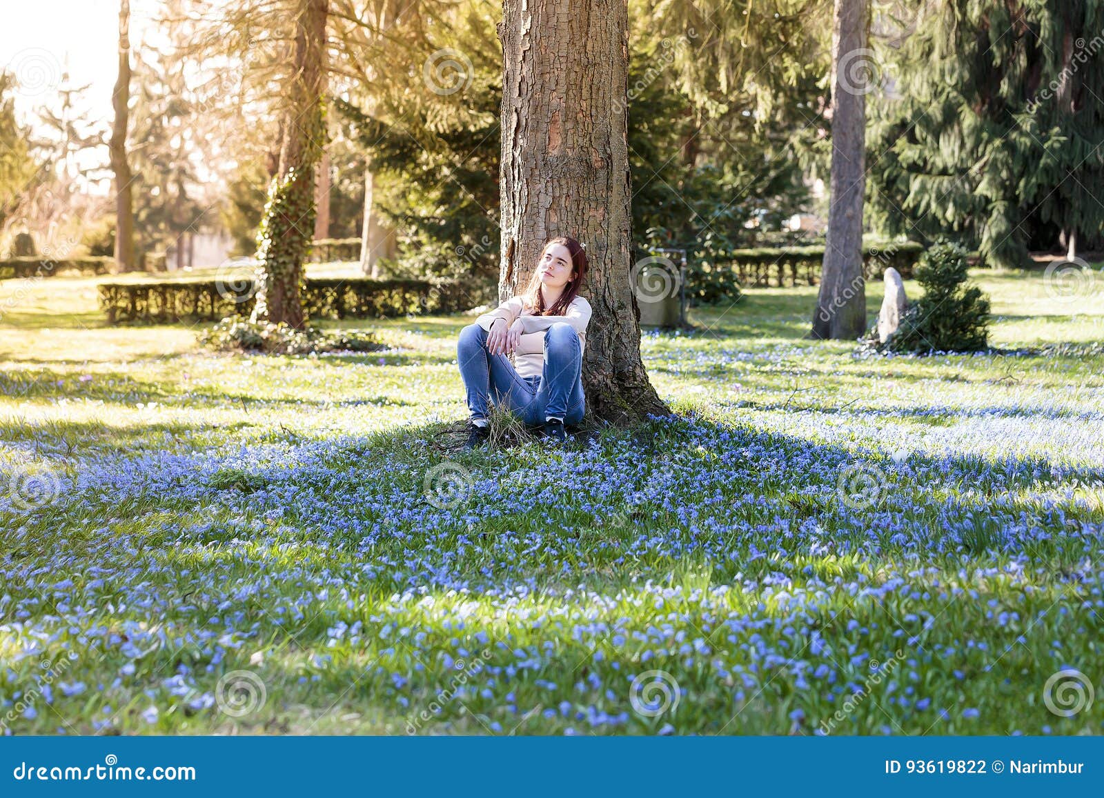 Young smiling woman sitting on a spring flower meadow