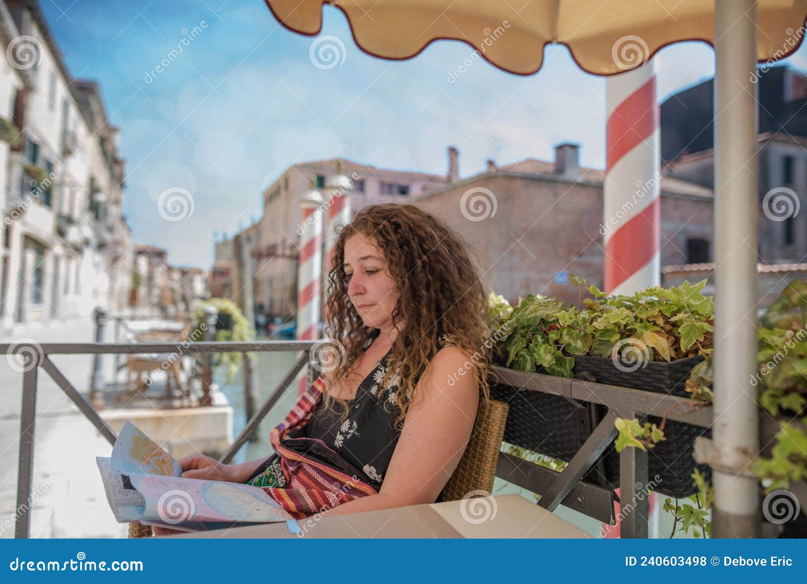 pretty woman sitting at the table of a restaurant on the edge of the little unknown canals of venice