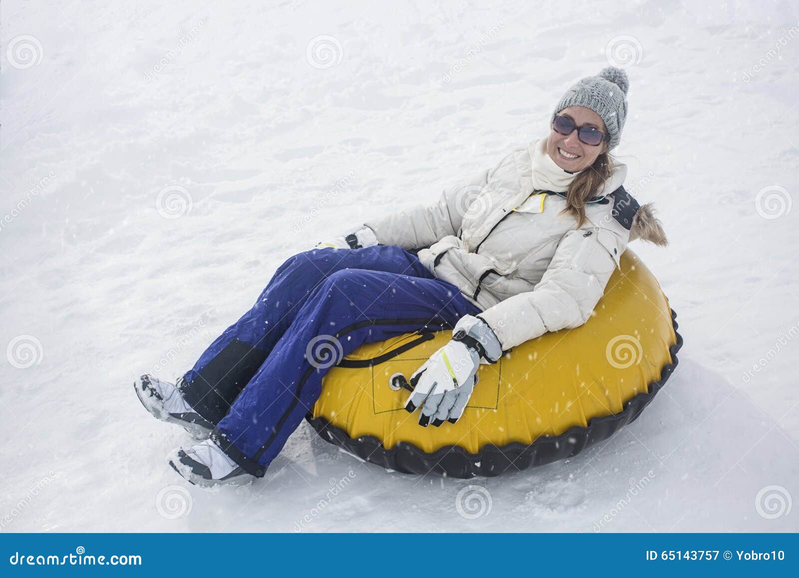 woman sledding down a hill on a snow tube