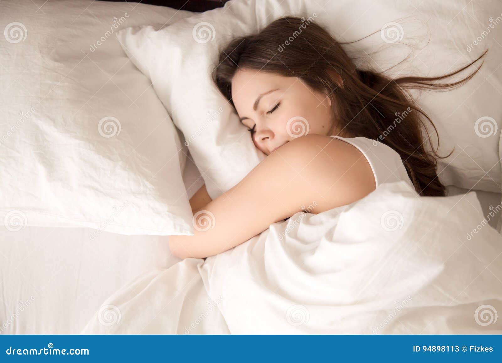 woman sleeping in bed hugging soft white pillow