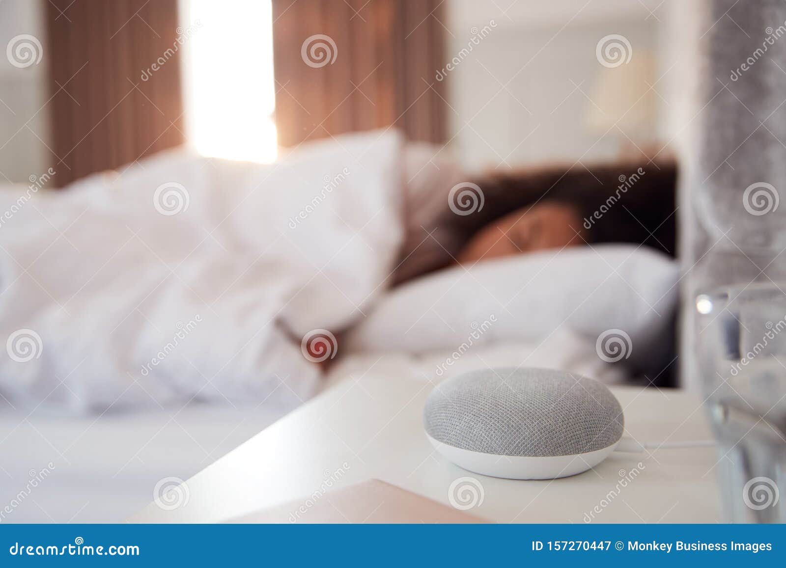 woman sleeping in bed with voice assistant on bedside table next to her