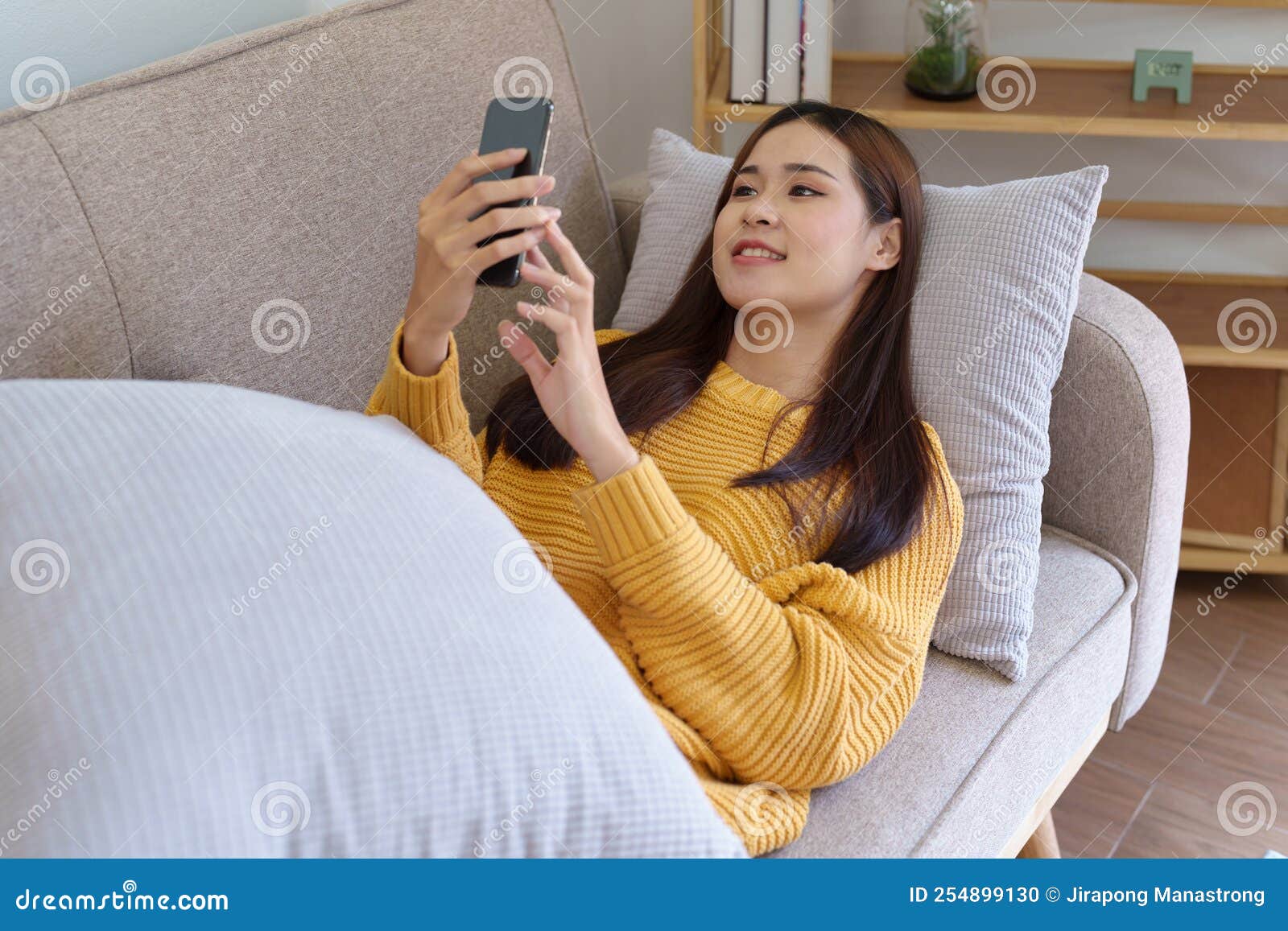 Woman Sleeping on Sofa at Home Ready To Use Mobile Phone Stock Photo