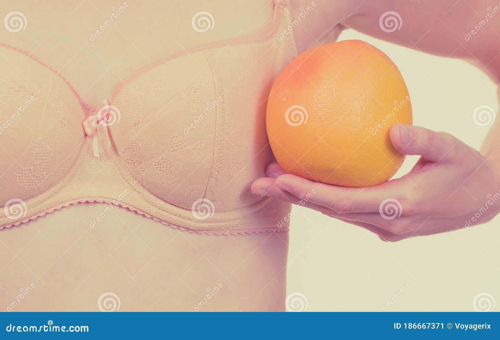 Slim Young Woman Small Boobs Puts Big Orange Fruit In Her Bra. Breast  Enlargement Size Correction Concept. Stock Photo, Picture and Royalty Free  Image. Image 143825659.