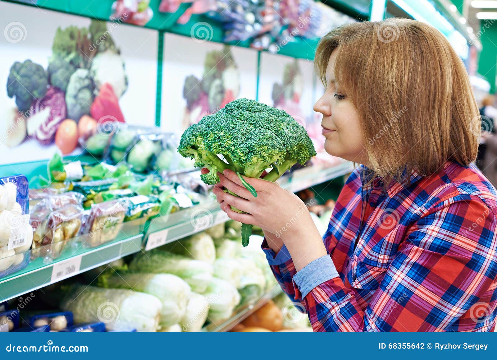 Woman Smelling Broccoli in Store, Checking for Freshness Stock Photo