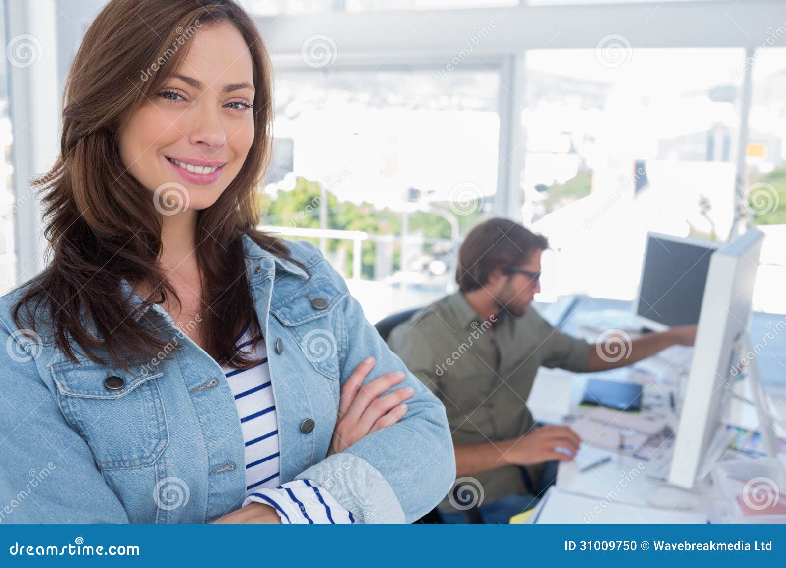 woman smiling in creative office with arms folde