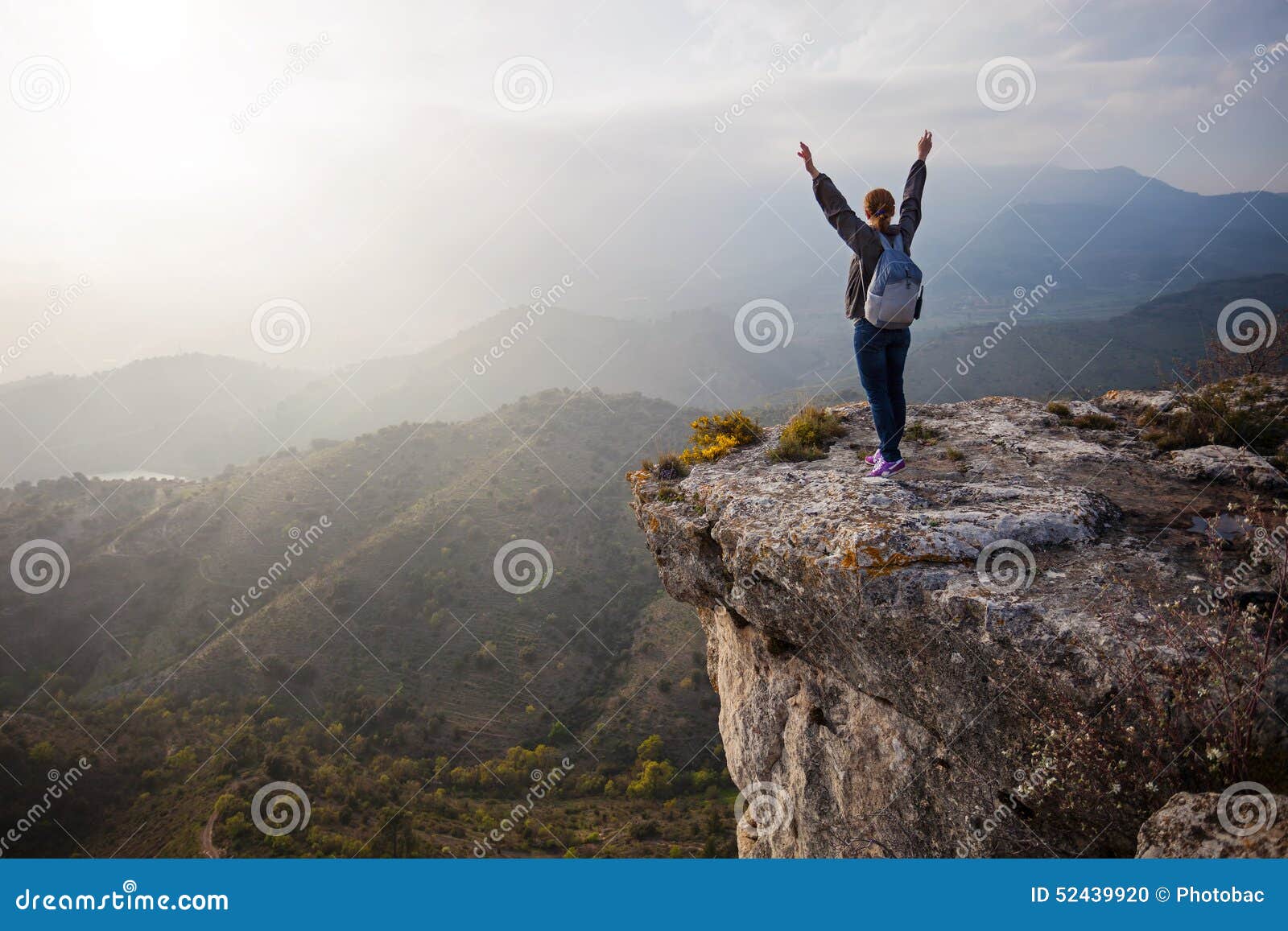 woman standing on cliff with outstretched arms