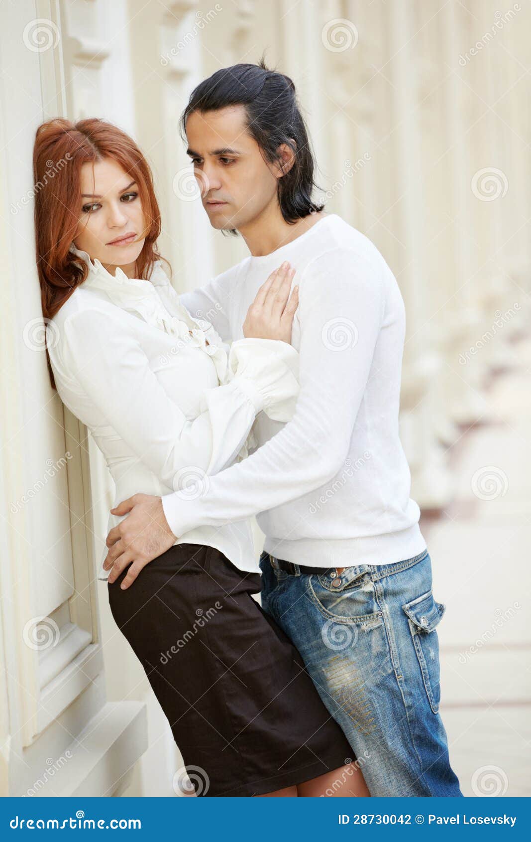 Woman Stands, Leaning at Wall and Man Embraces Her Stock Photo photo