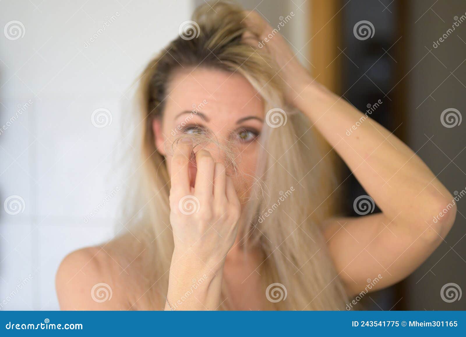 woman staring in dismay at tufts of loose hair