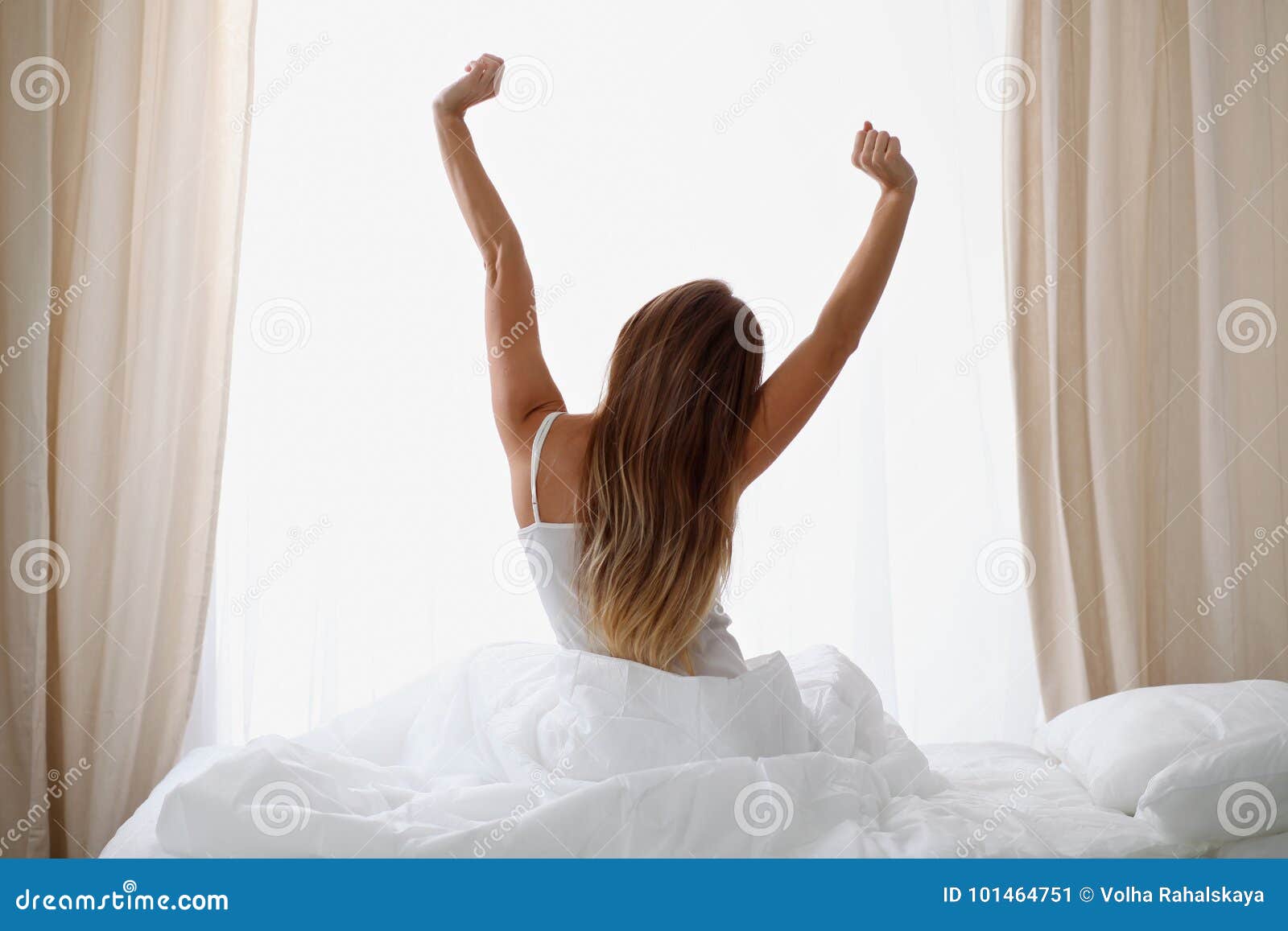 woman stretching in bed after wake up, back view, entering a day happy and relaxed after good night sleep. sweet dreams