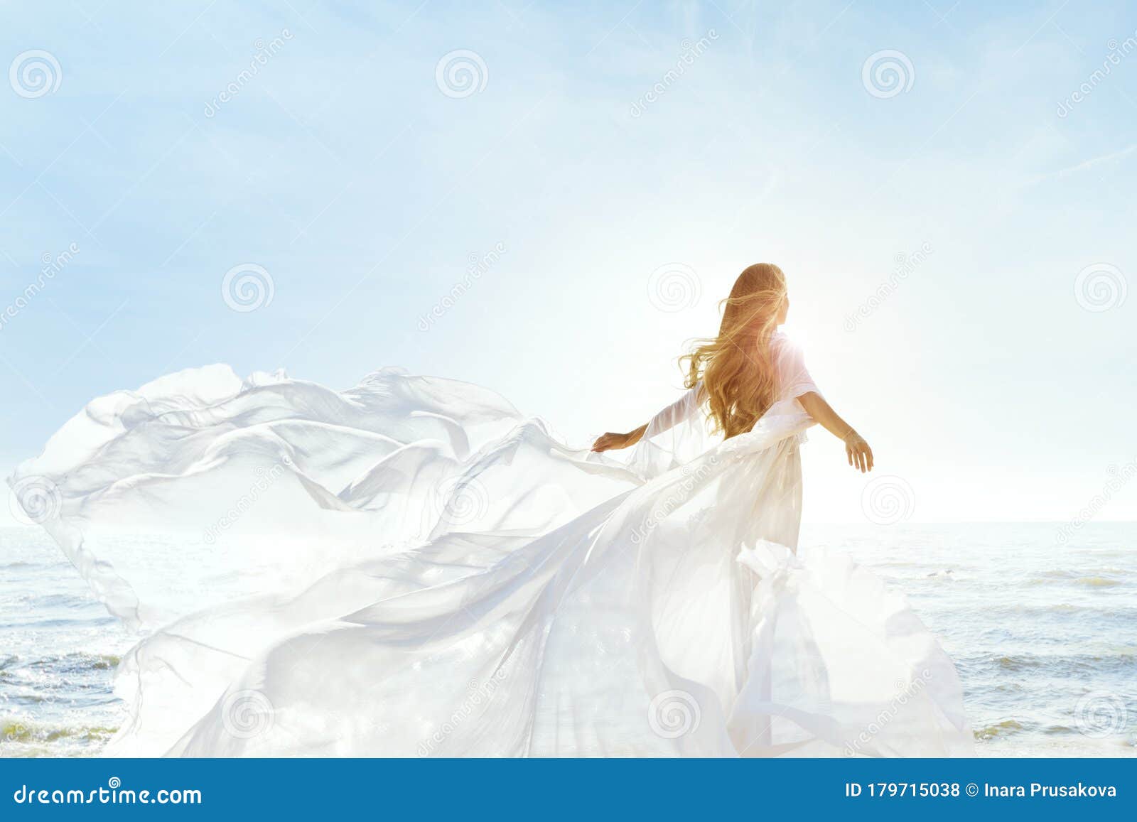 woman on sunny sea beach in white fluttering dress, fashion model back rear view, silk cloth waving on wind