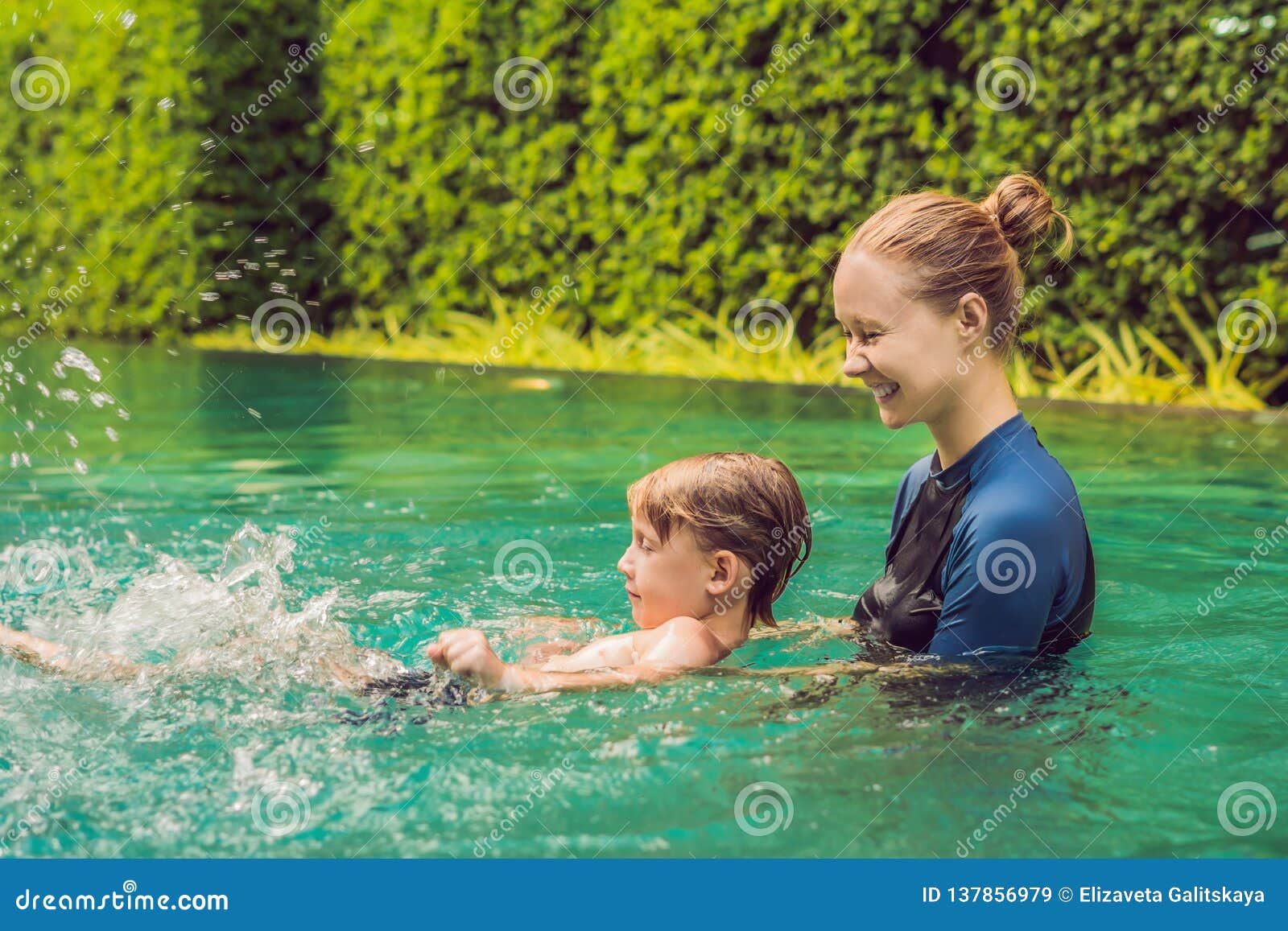 woman swimming instructor for children is teaching a happy boy to swim in the pool