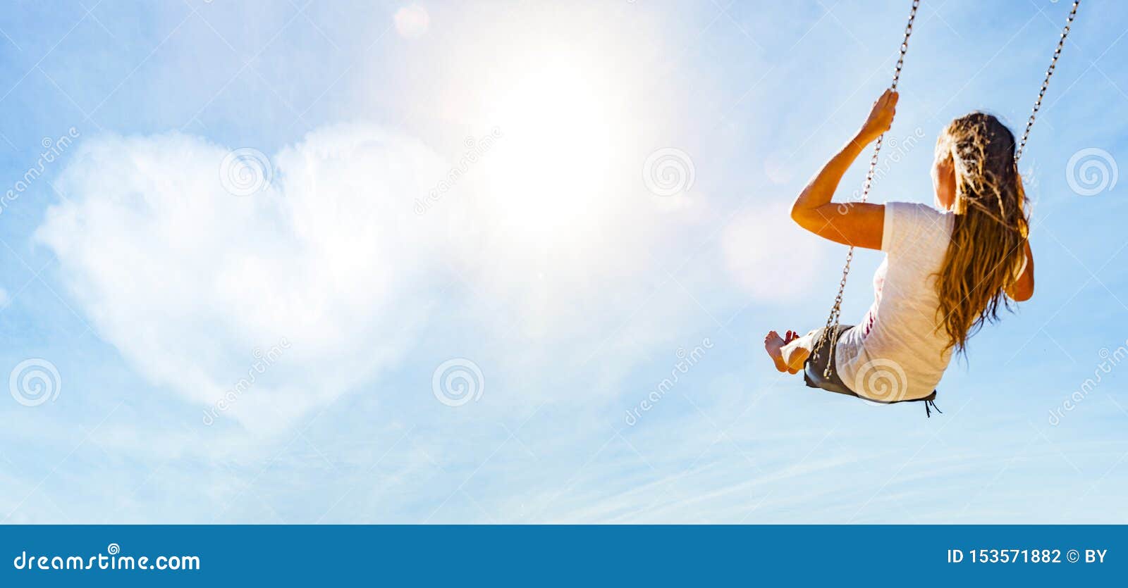 woman on a swing with blue sky and heart-d cloud