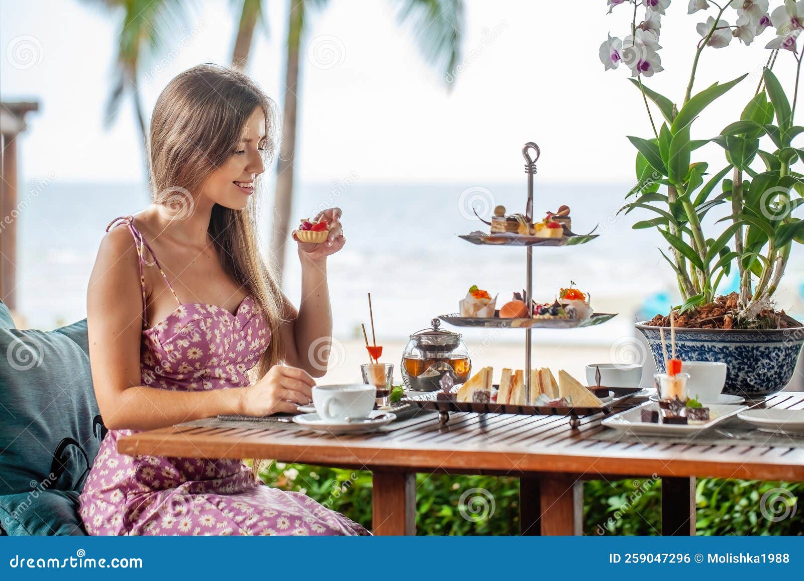 woman take cake out of afternoon tea set in sea outdoors restaurant
