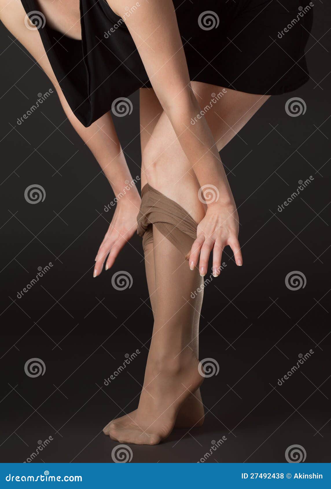 Woman takes off stockings on a black background.