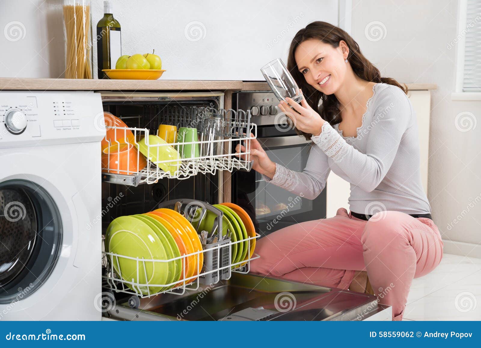 woman taking drinking glass from dishwasher