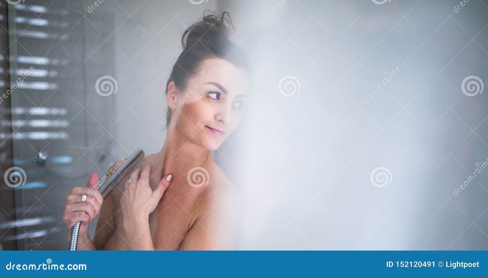 Beautiful naked woman washing her hair while taking shower 