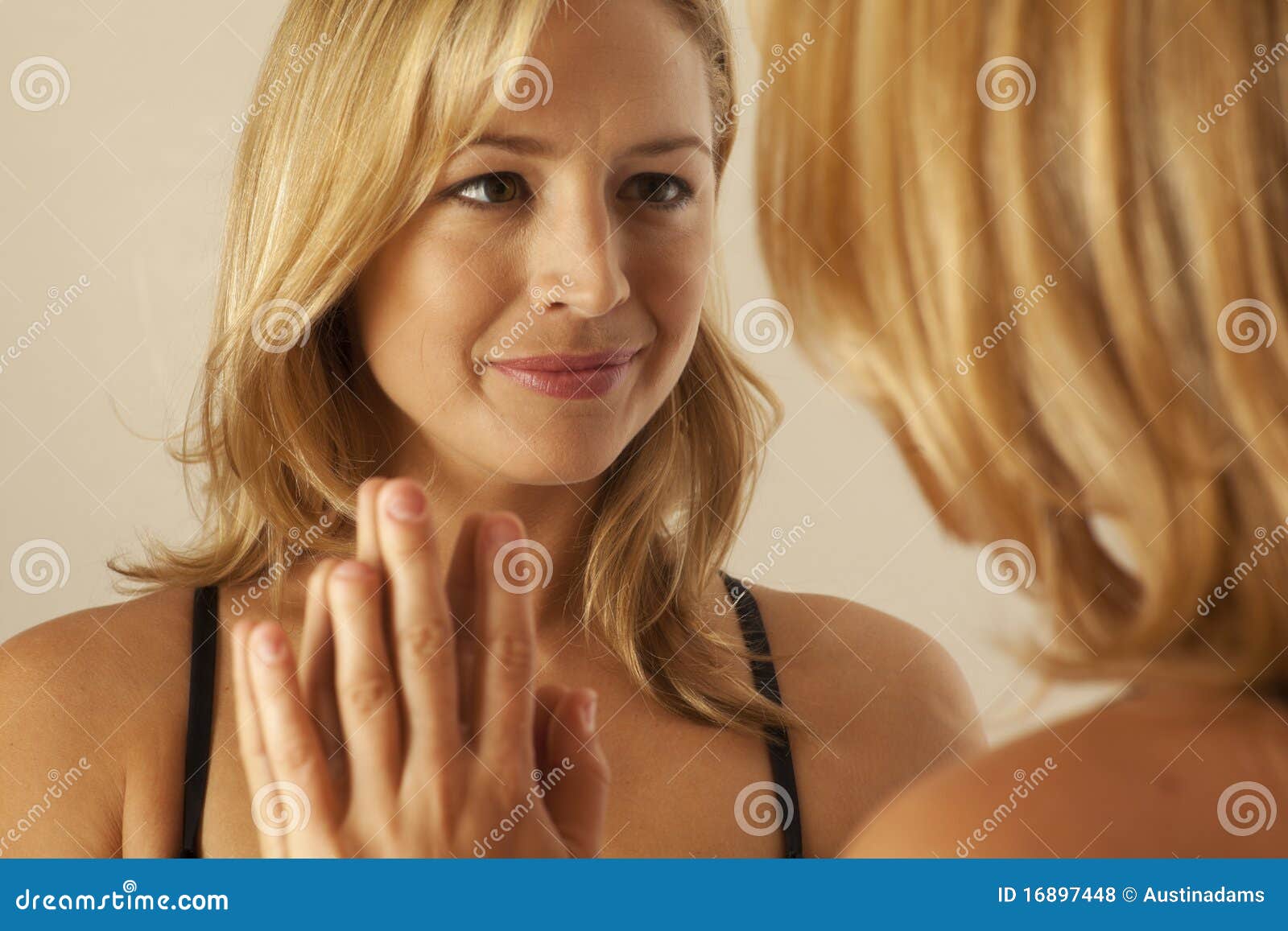 woman touching mirror while looking at reflection