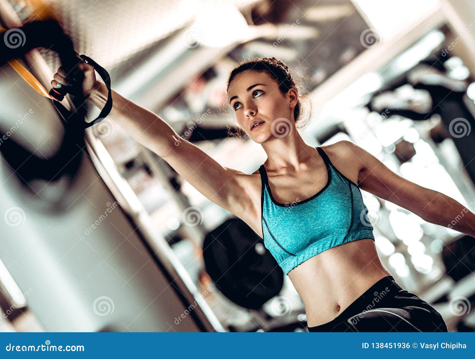 Women training arms with trx fitness straps in the gym doing push ups train  upper body chest shoulders pecs triceps. Stock Photo