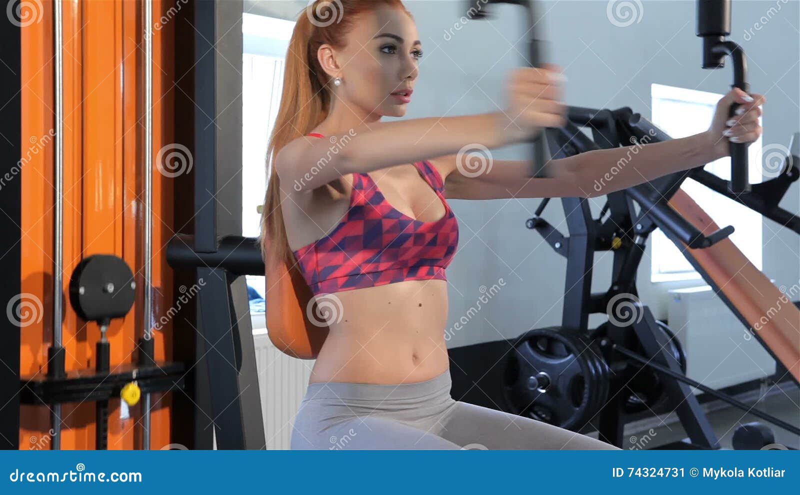 Woman Trains Her Chest Muscles on Pec Deck Machine at the Fitness