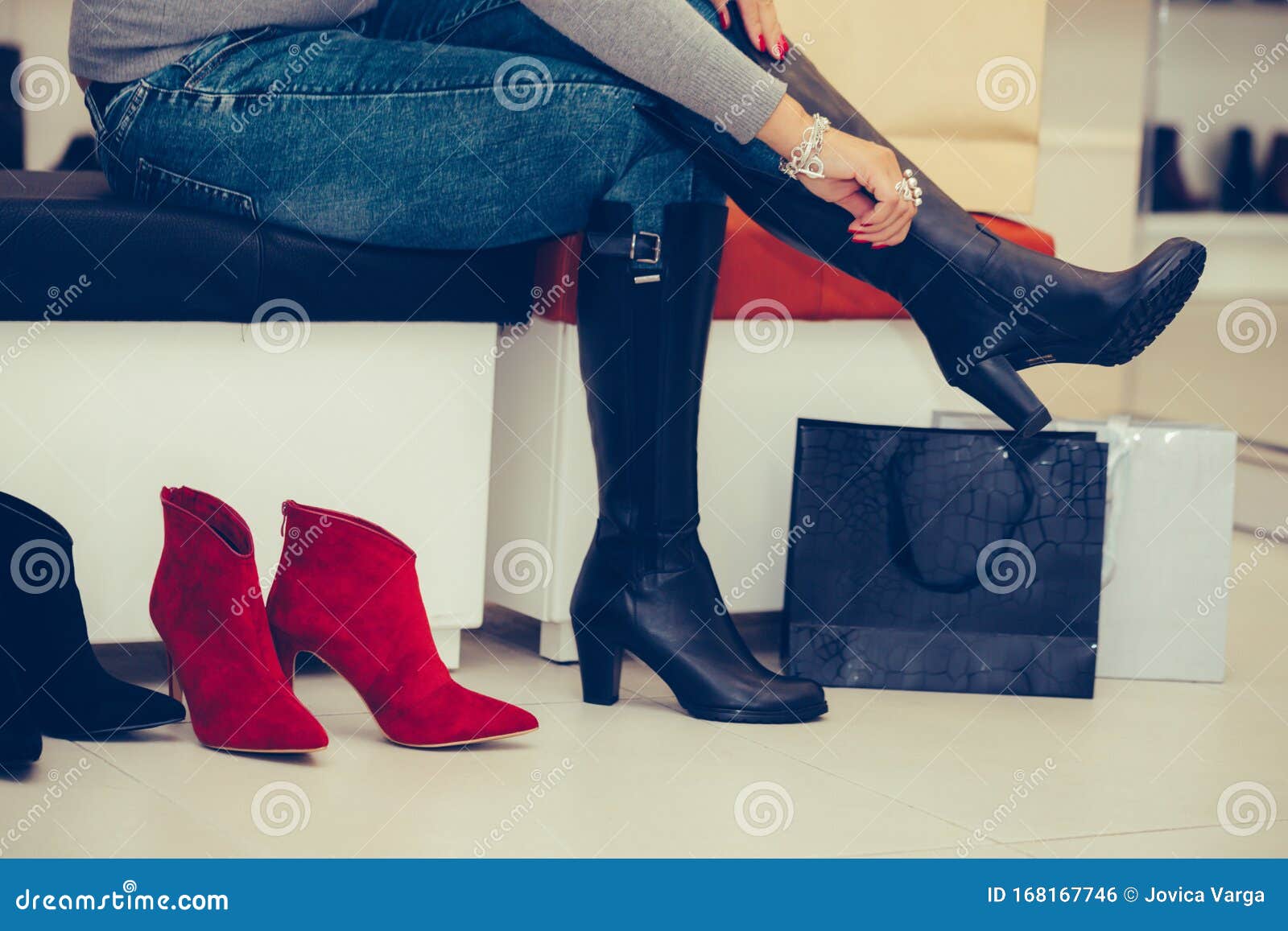 Woman Trying on New Pair of Deep Boots with High Heels while Sitting at ...