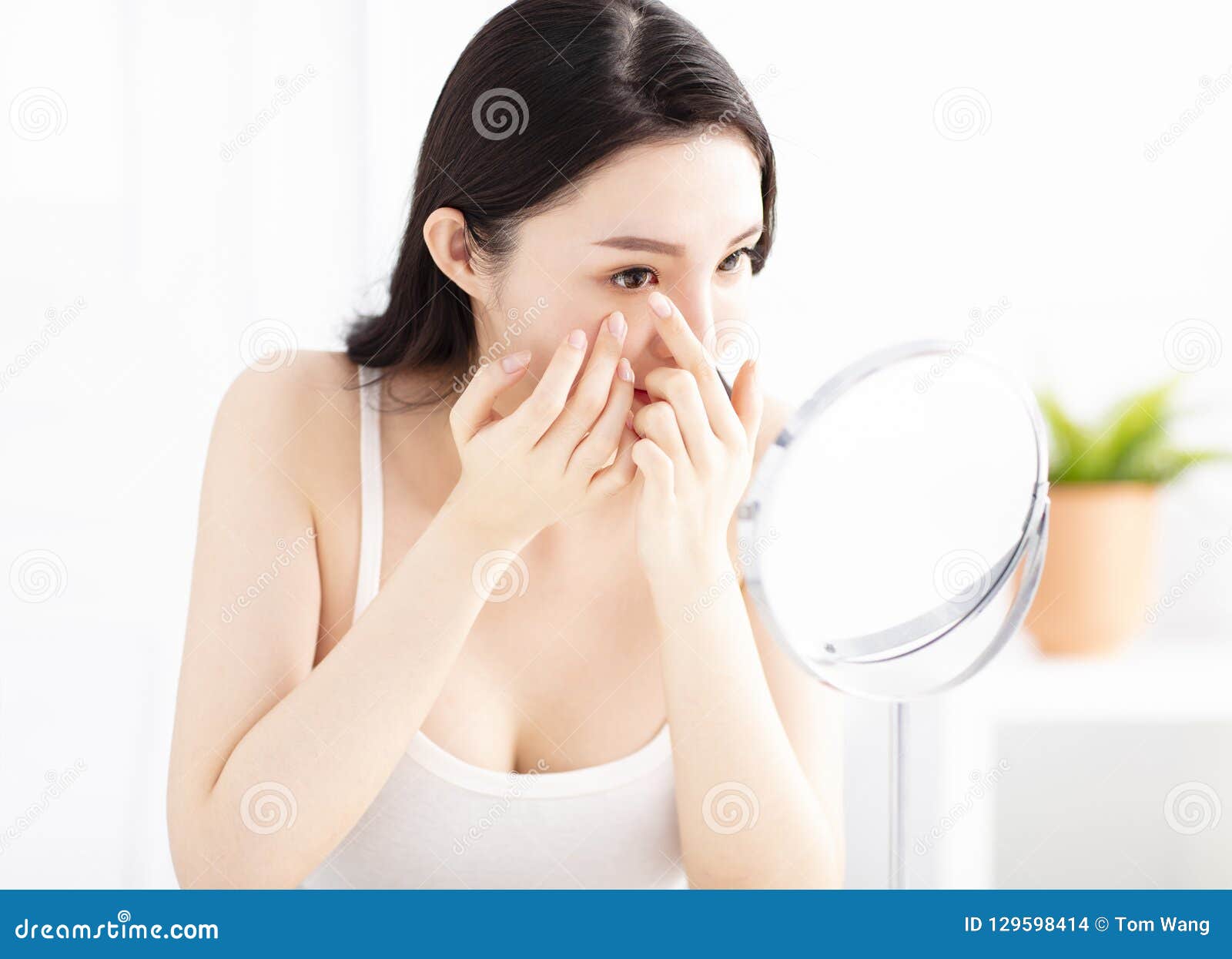 woman trying to apply contact lenses in front of mirror