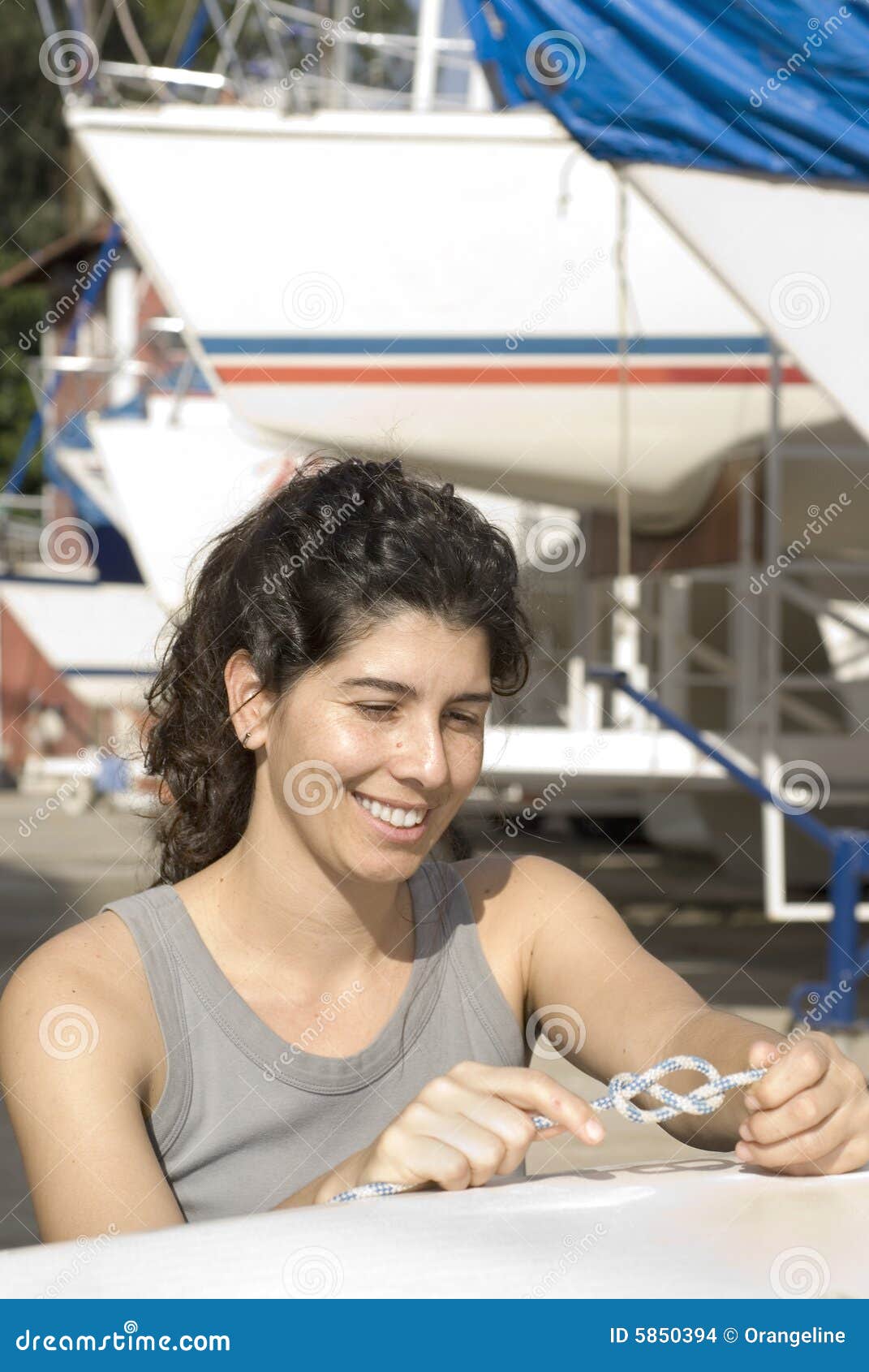 woman tying knot on sailboat - vertical stock photo