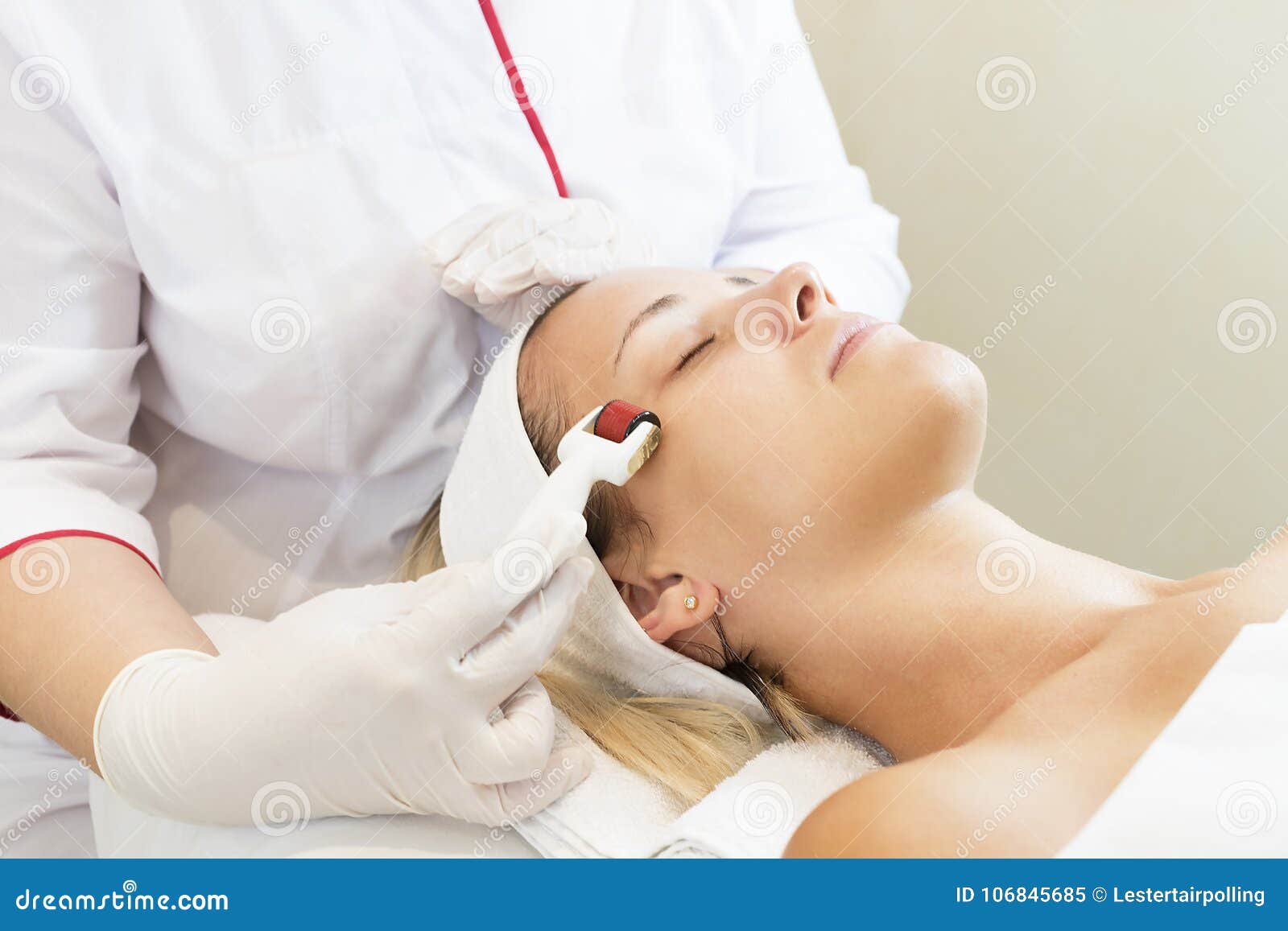 woman undergoes the procedure of medical micro needle therapy with a modern medical instrument derma roller.